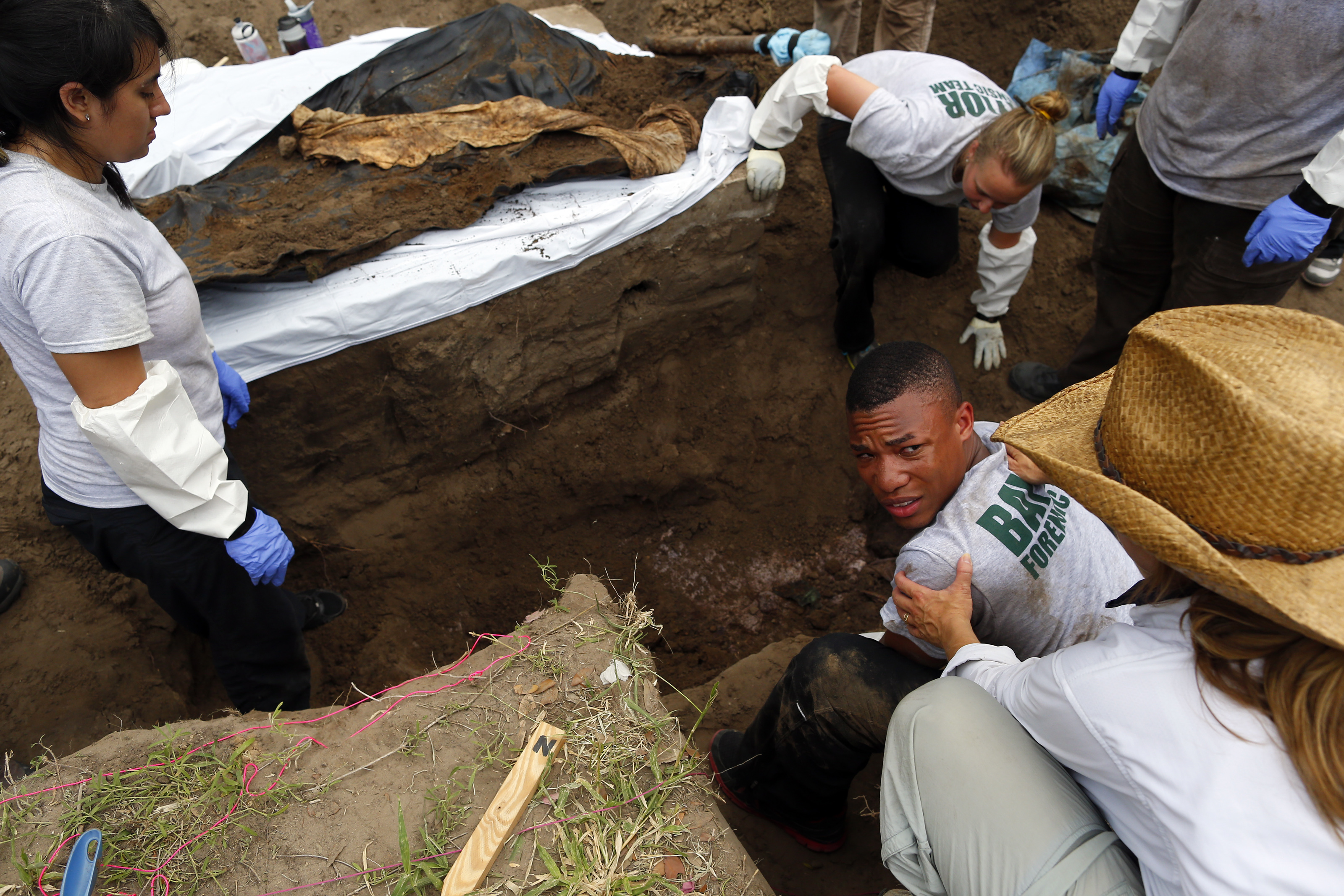 Xavier Colbert, 22, a Baylor senior, was helped by a professor as he lifted a body out of a grave. He is part of a team of forensics students working to exhume bodies of unidentified migrants.