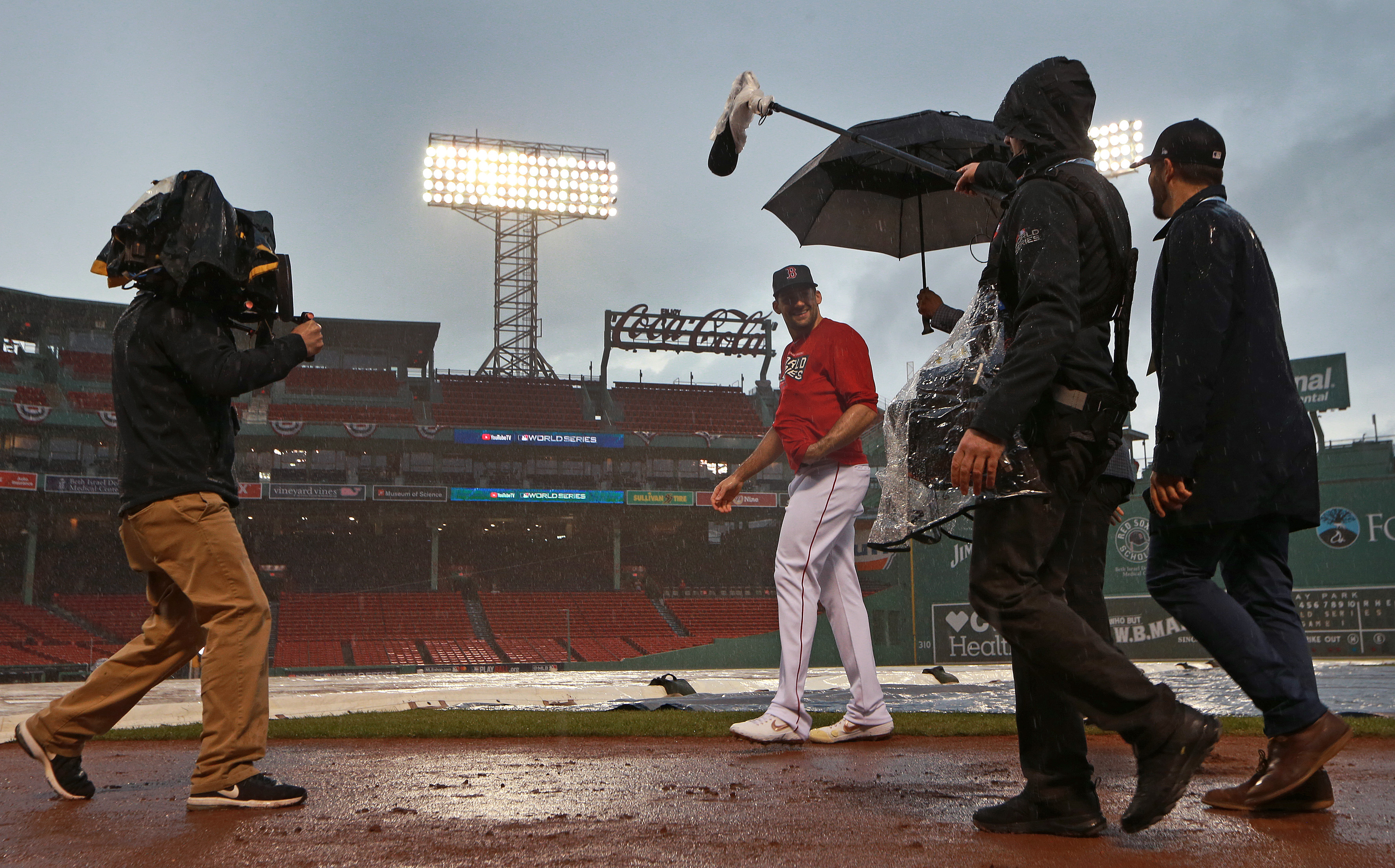 Red Sox pitcher Nathan Eovaldi is shadowed by an umbrella-toting camera crew as heavy rain fell at Fenway Park at about 4:30 p.m.