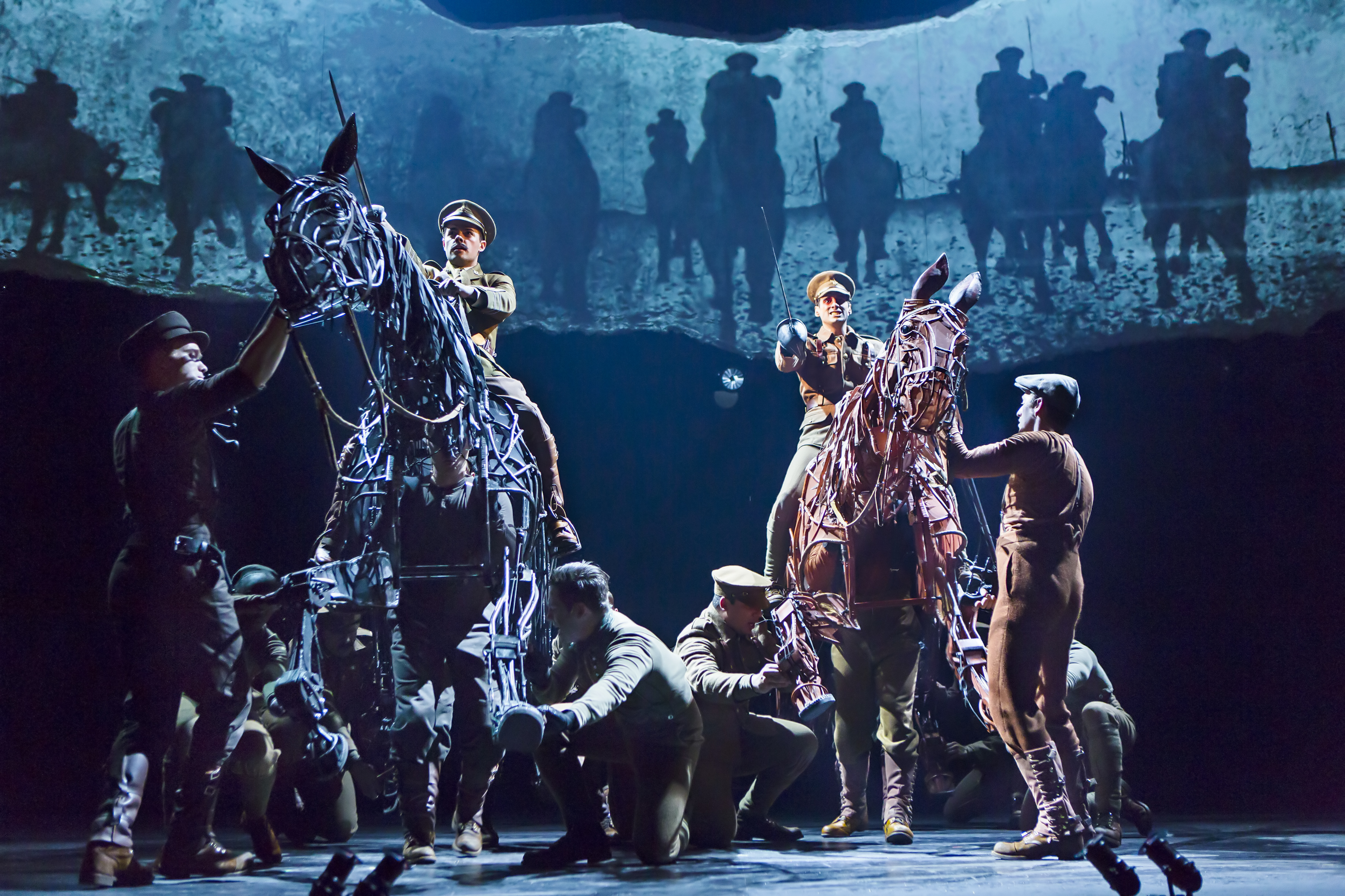 Grayson DeJesus and Michael Wyatt Cox sit atop horses, with the puppeteers inside, during a performance of “War Horse.”