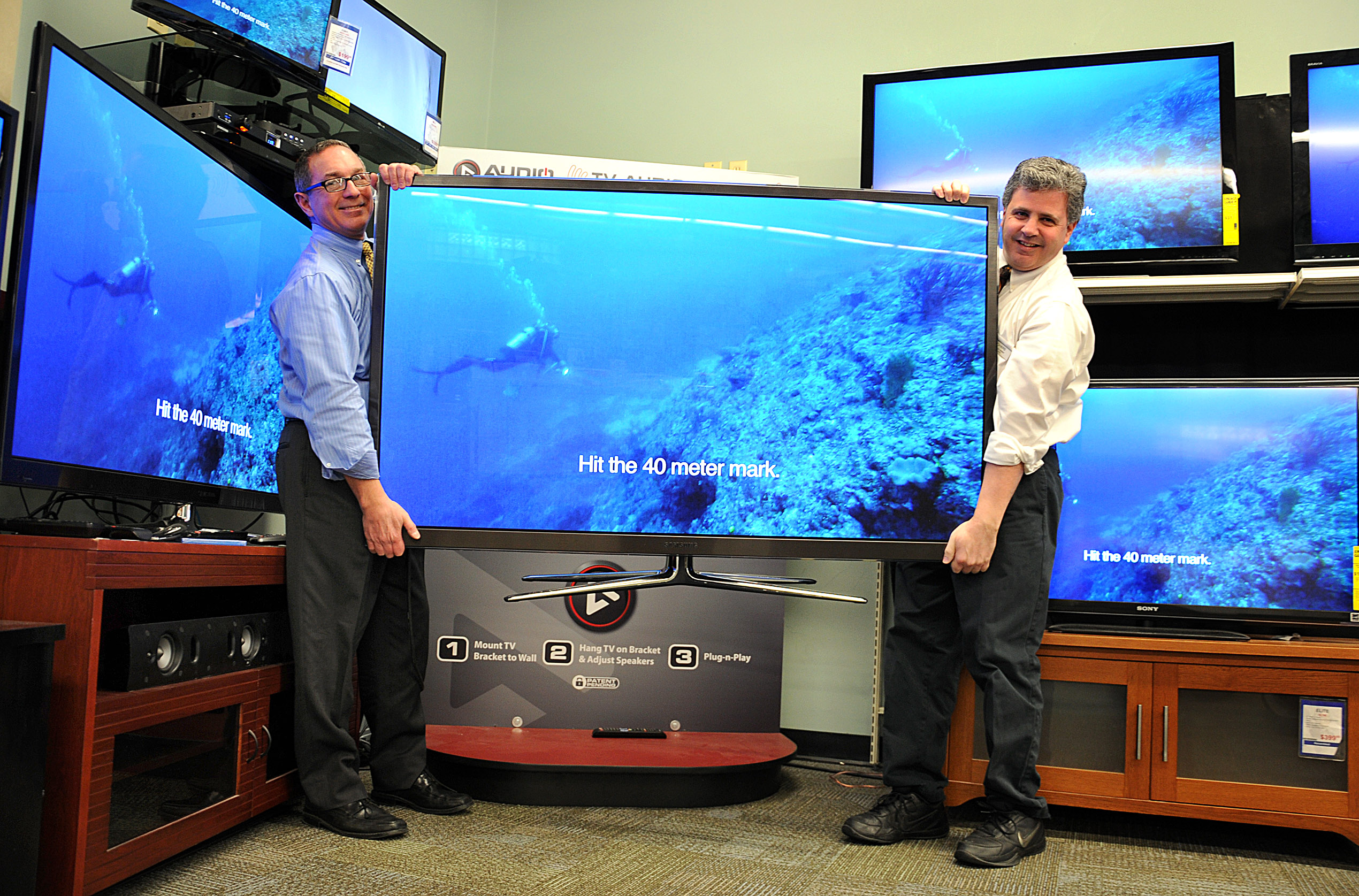At the George Washington Toma TV store, owner George Toma (left) and salesman Richard Shuman moved a 64-inch TV.