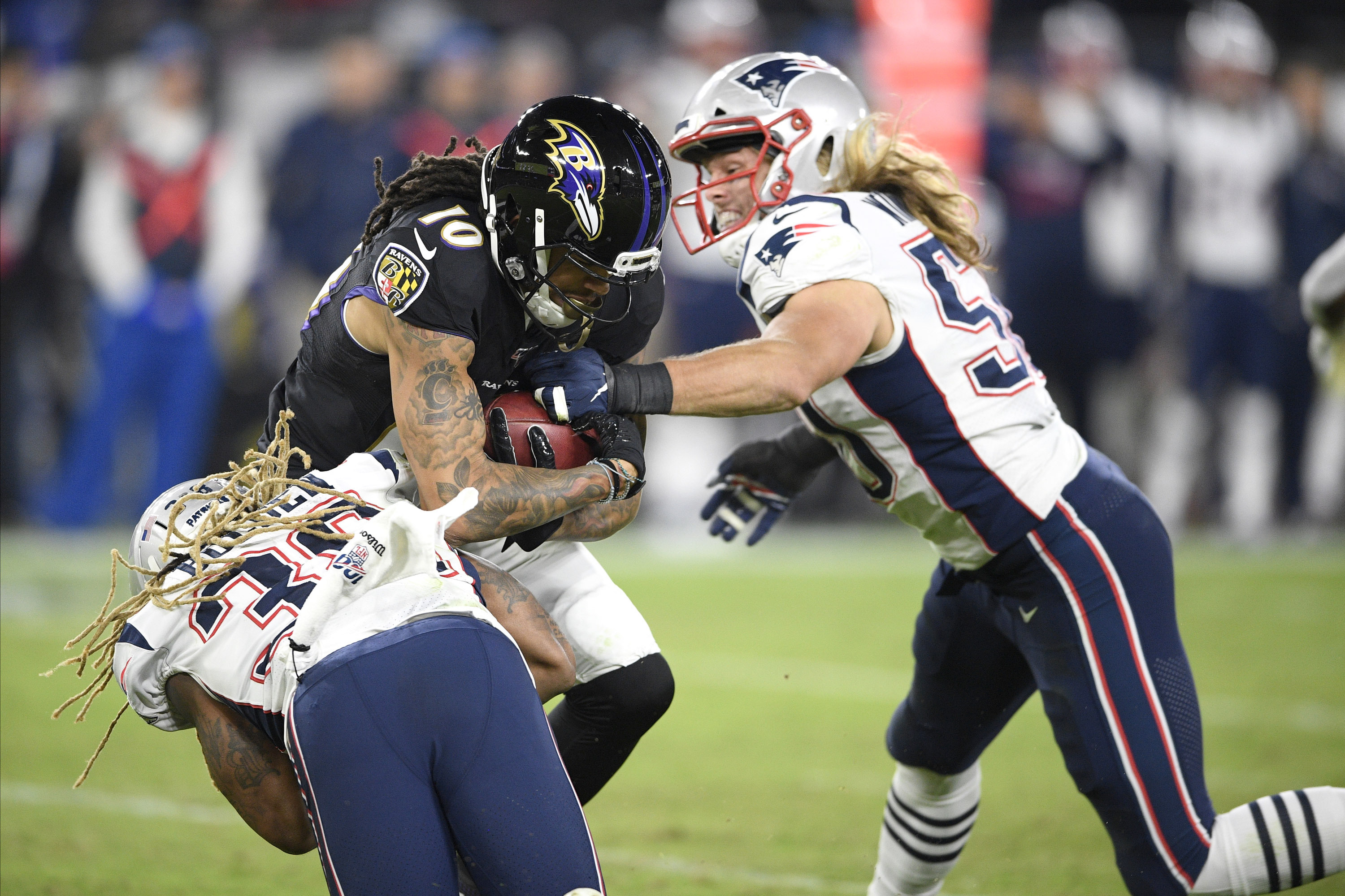 Brandon Bolden (left) and Chase Winovich move in for a tackle on Baltimore returner Chris Moore.