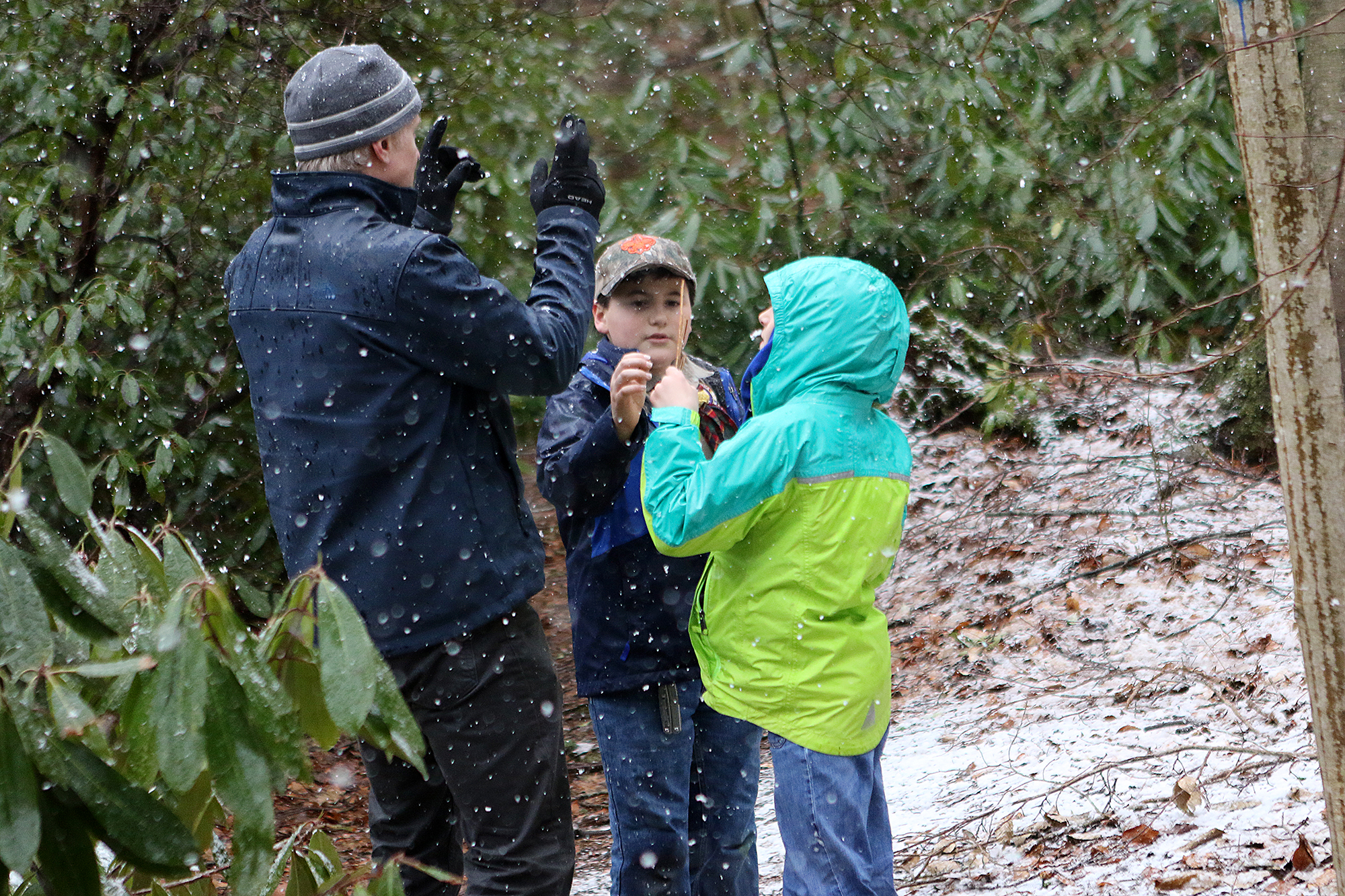 Cub Master Todd Cooper shows Zac Carvalho and Cia Donohoe what kind of sticks to use for their fire.