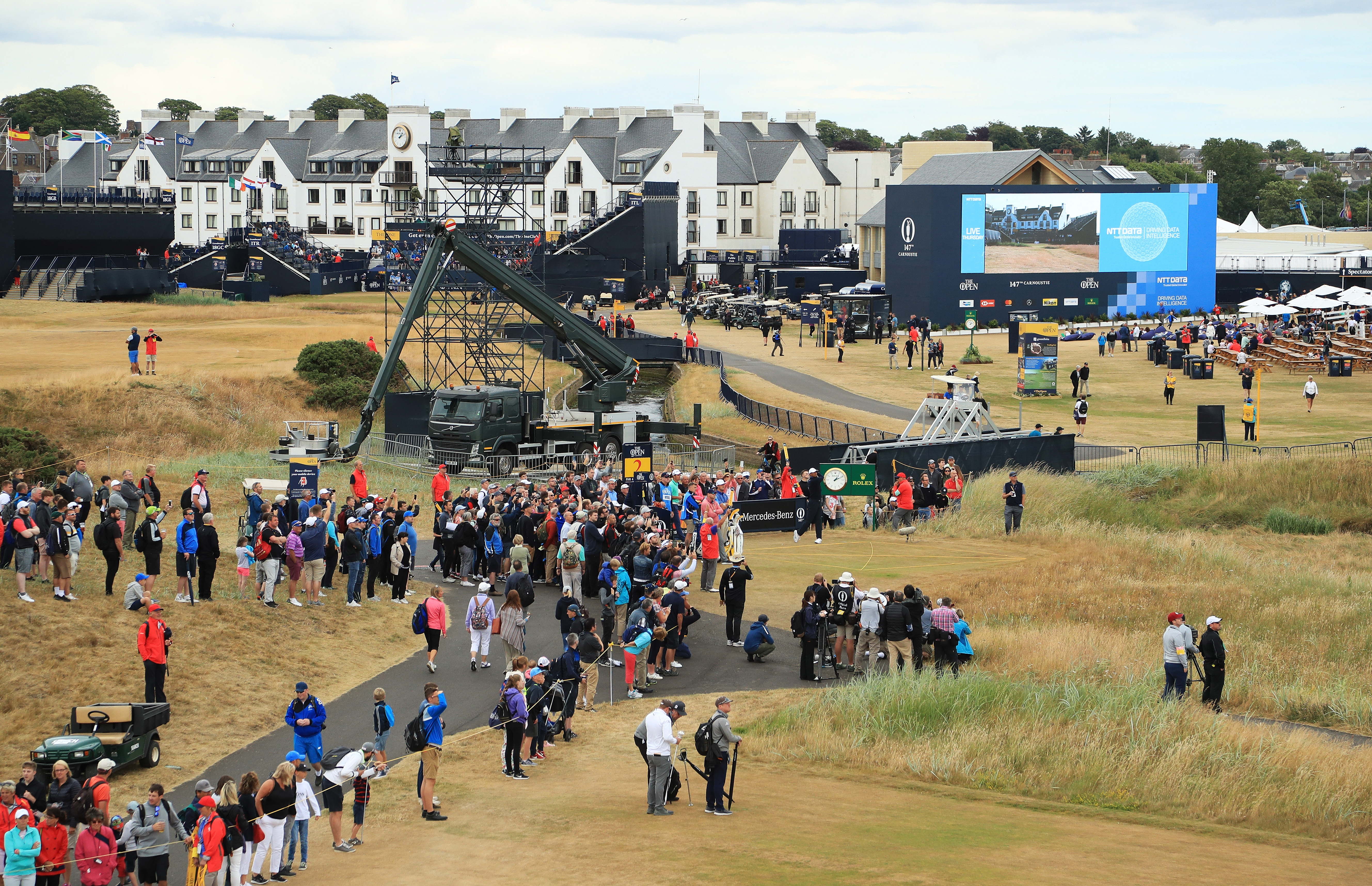 Spectators watch Tiger Woods hit a tee shot on the second hole during a practice round for the British Open.