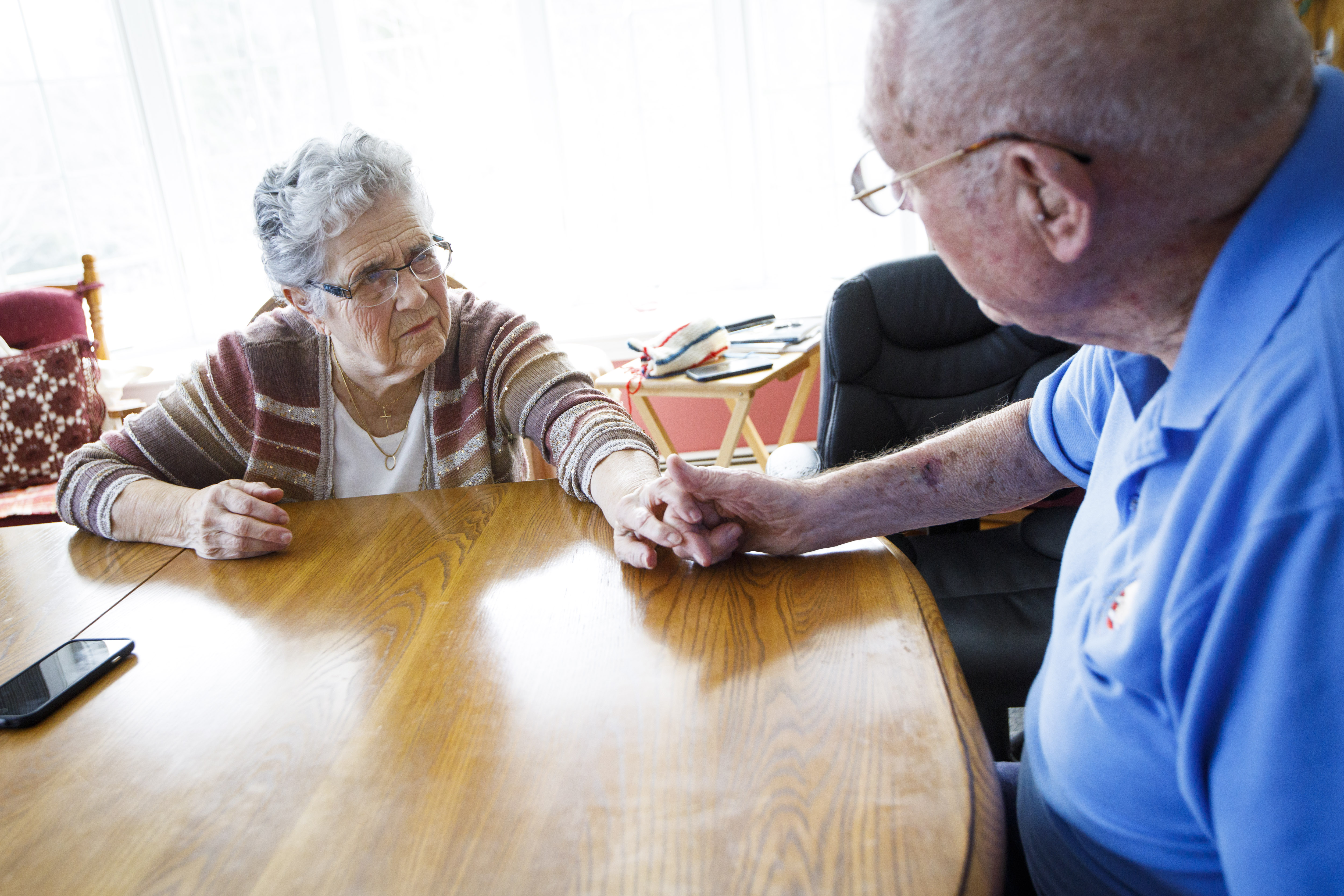 Janice McWhinnie holds her husband Robert's hand in their home. The family plans to sue the hospital for negligence.