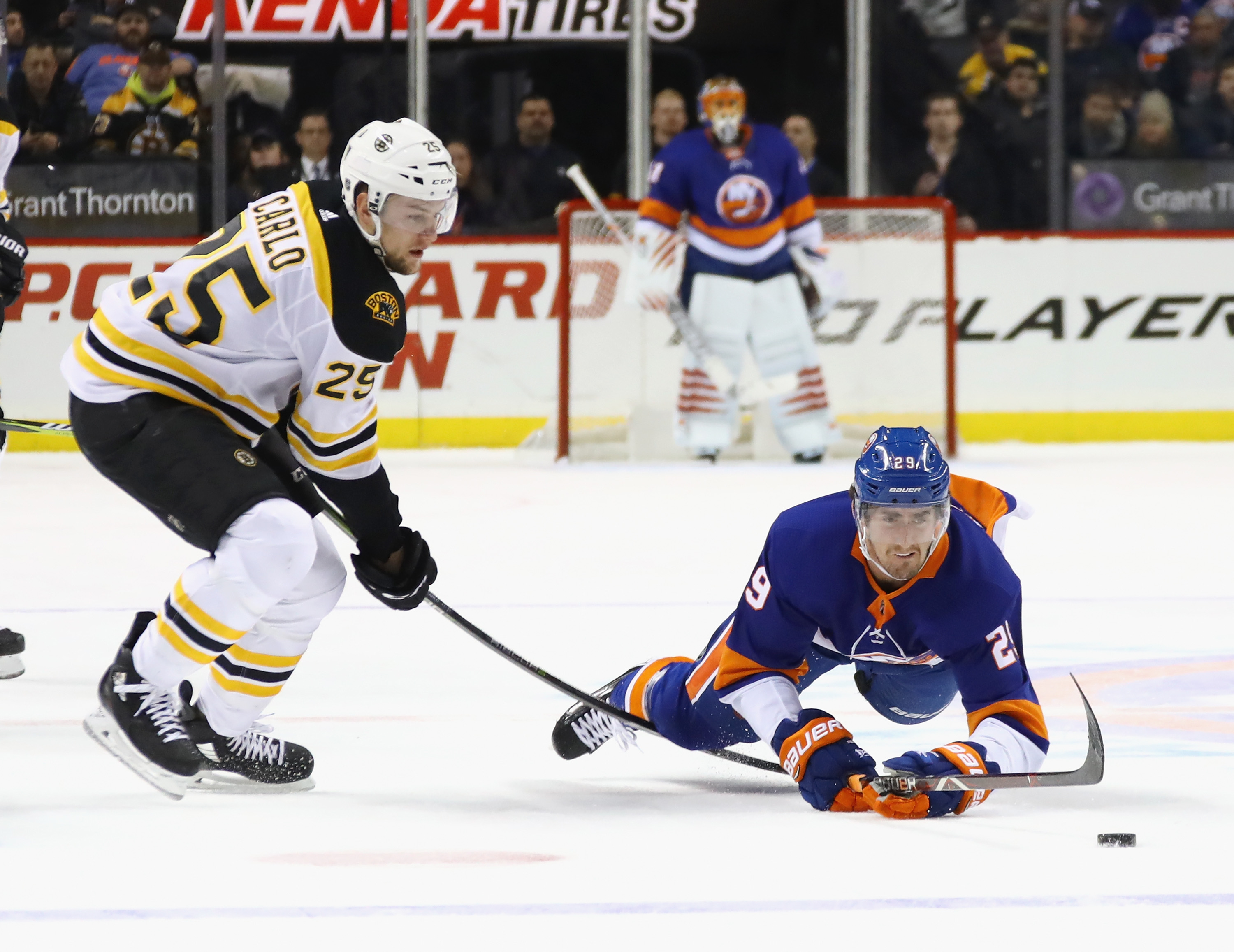 The Bruins’ Brandon Carlo and New York’s Brock Nelson Islanders battle for the puck.