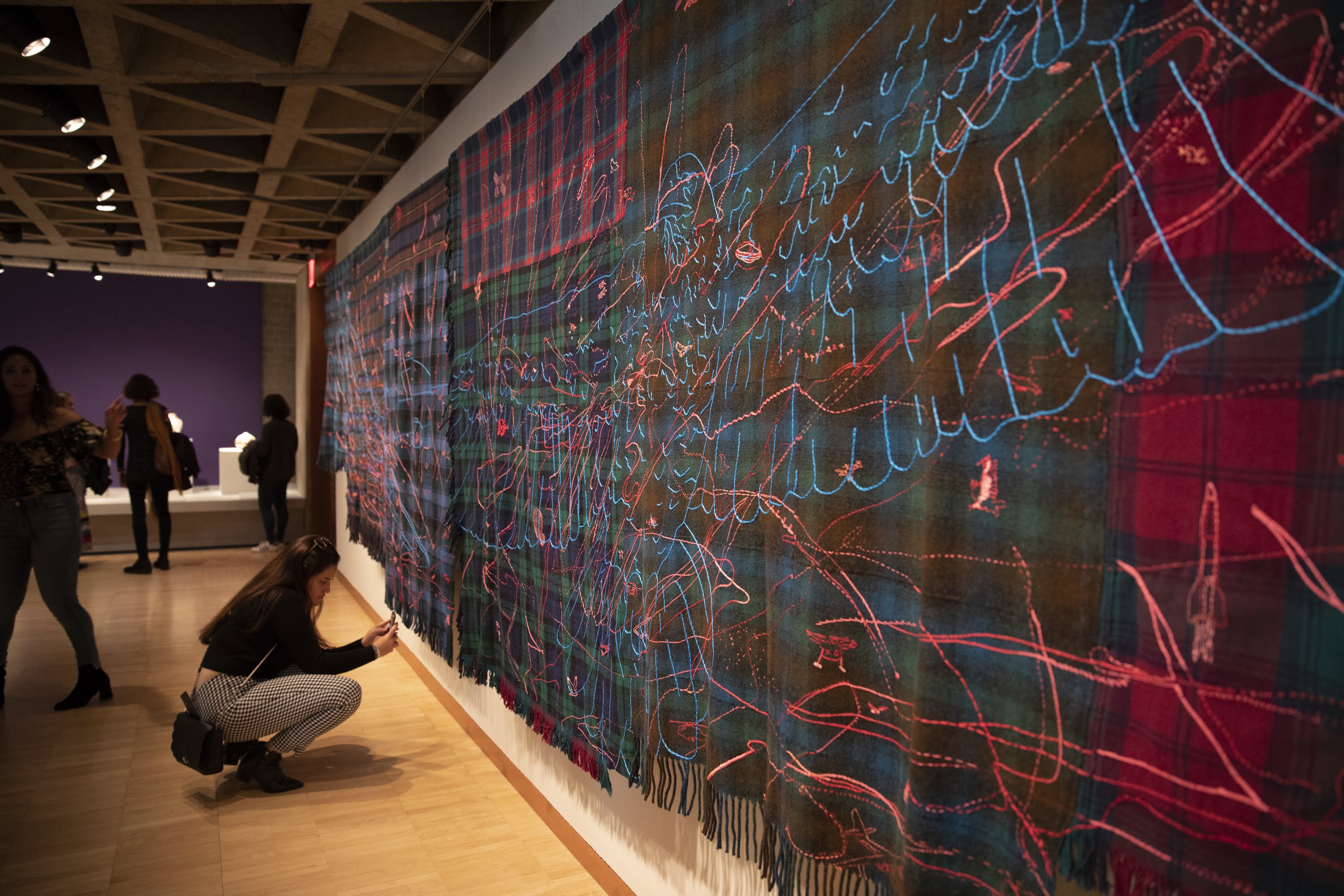 A visitor interacts with Marie Watt’s “First Teachers Balance the Universe.”