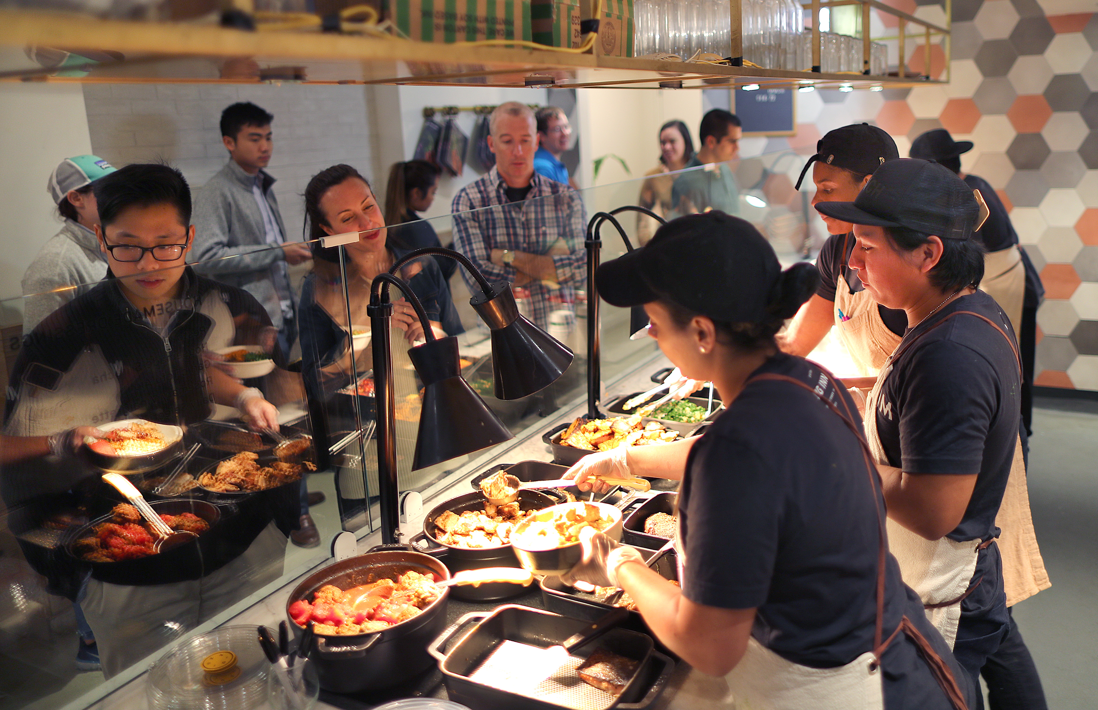 Customers wait in line as their bowls are prepared at Dig Inn.