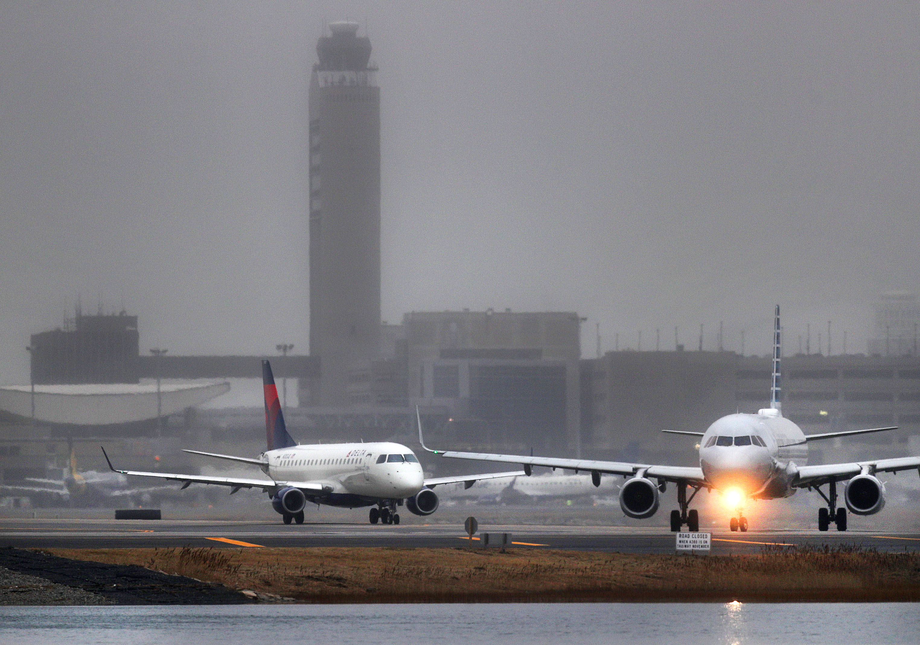 The Logan Airport control tower loomed in the distance as jets lined up for takeoff. The government shutdown may affect TSA workers and air traffic controllers.