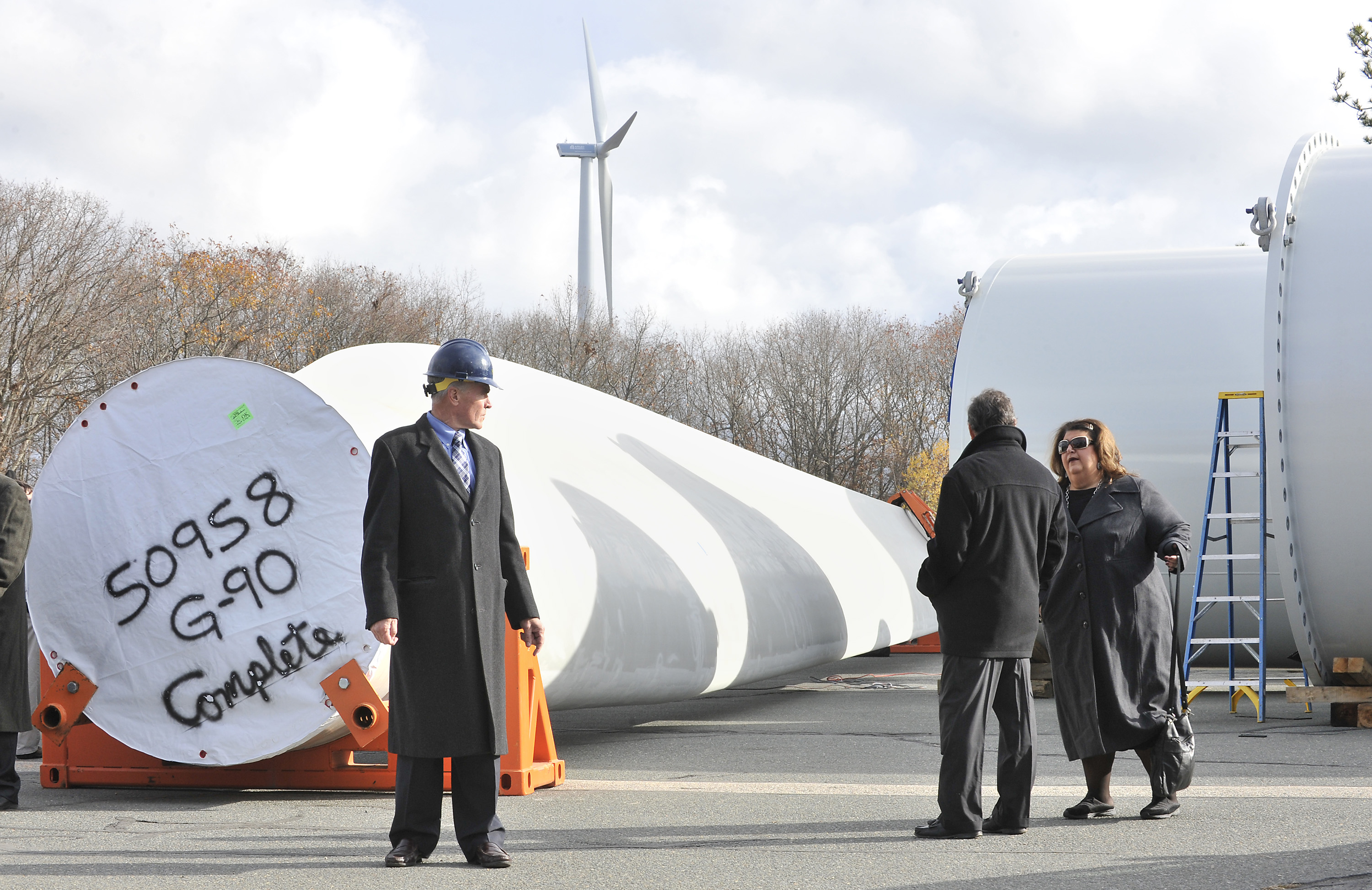 Jim Sweeny, president of developer Sustainable New Energy stands beside the base of one of the blades of the wind turbine that will be erected at Gloucester Engineeering in the Blackburn Industrial park as residents arrive for a ceremony to sign one of the blades before it is erecteed.