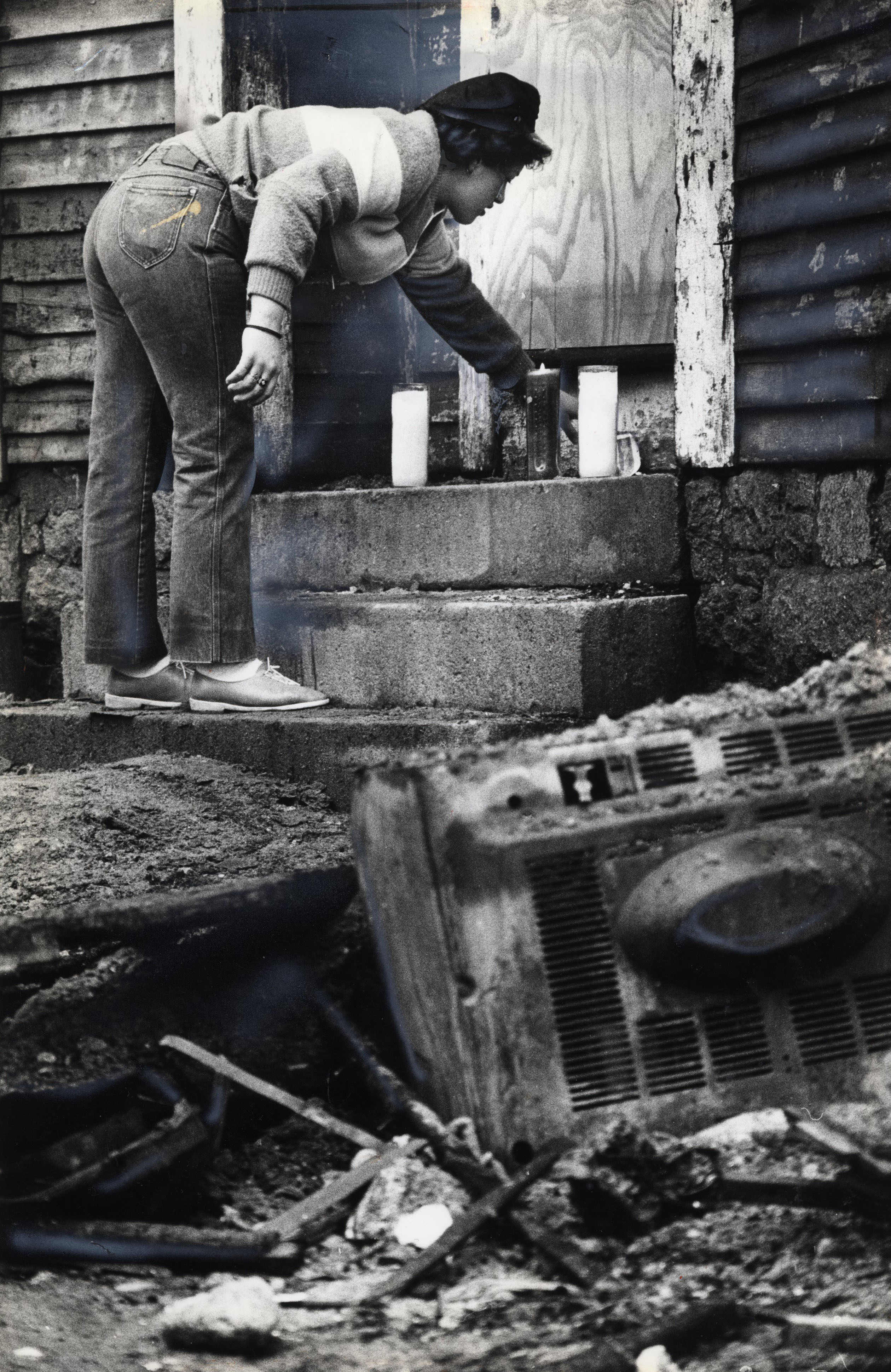 A saddened neighbor arranges lit candles on front steps after the 1982 blaze.
