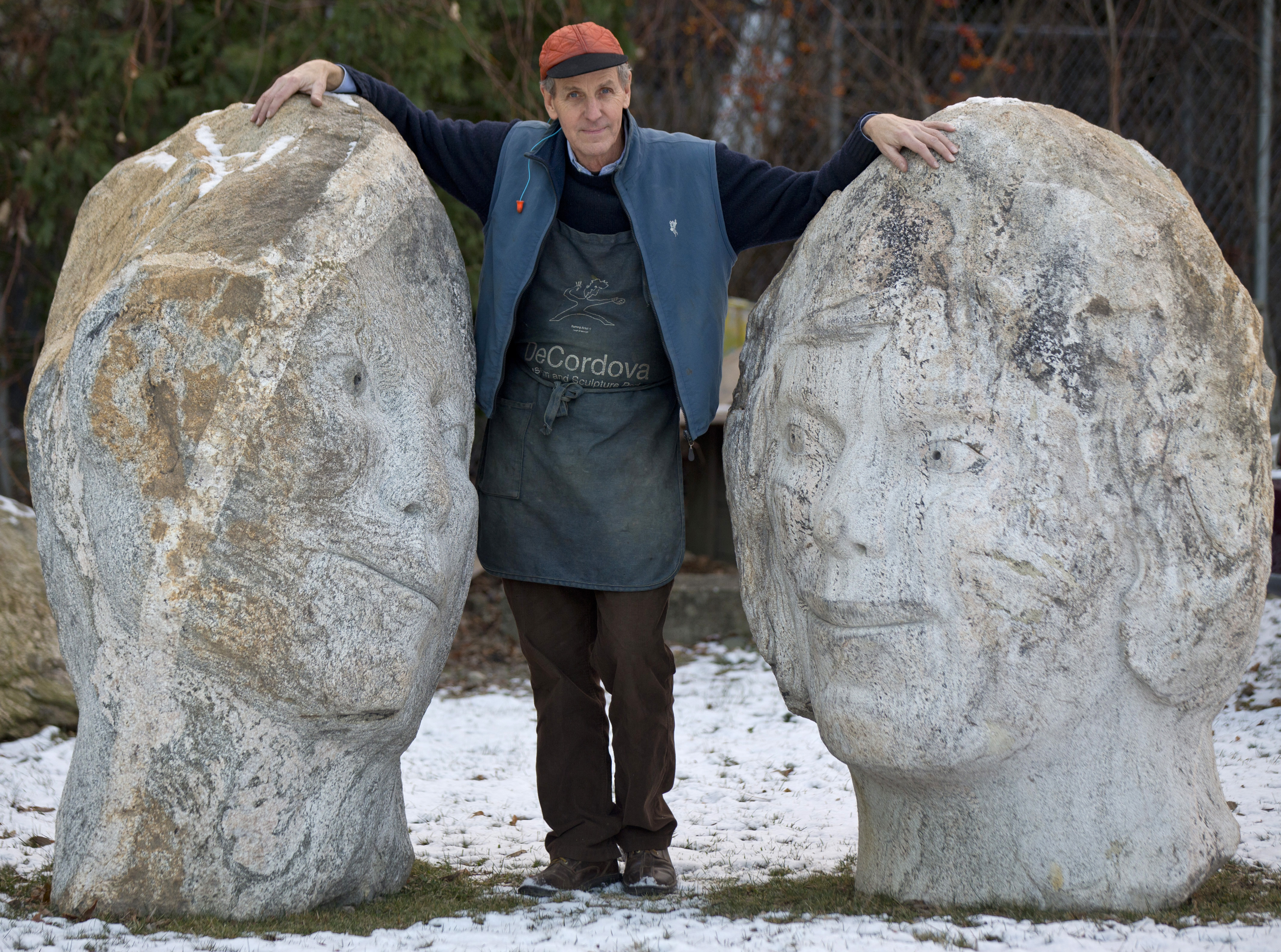 Sculptor Joe Wheelwright standing next to his granite pieces called “Loving Stones,” outside the deCordova Sculpture Garden and Museum.
