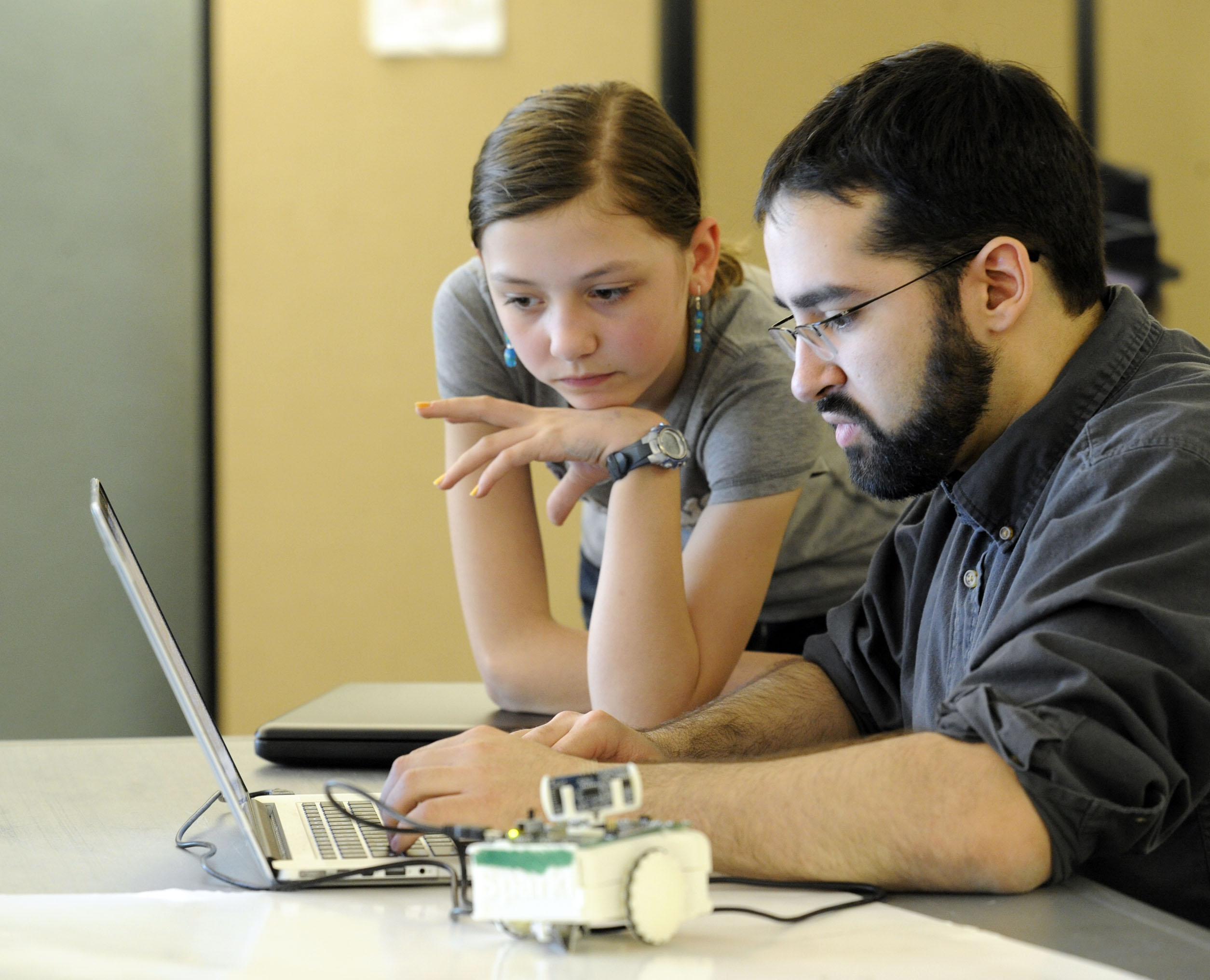 With 12-year-old Karina Heinold of Westford looking on, Joe Schlesinger enters a program for Sparki the robot. ArcBotics of Cambridge is using Kickstarter to raise money to fund production of the device.
