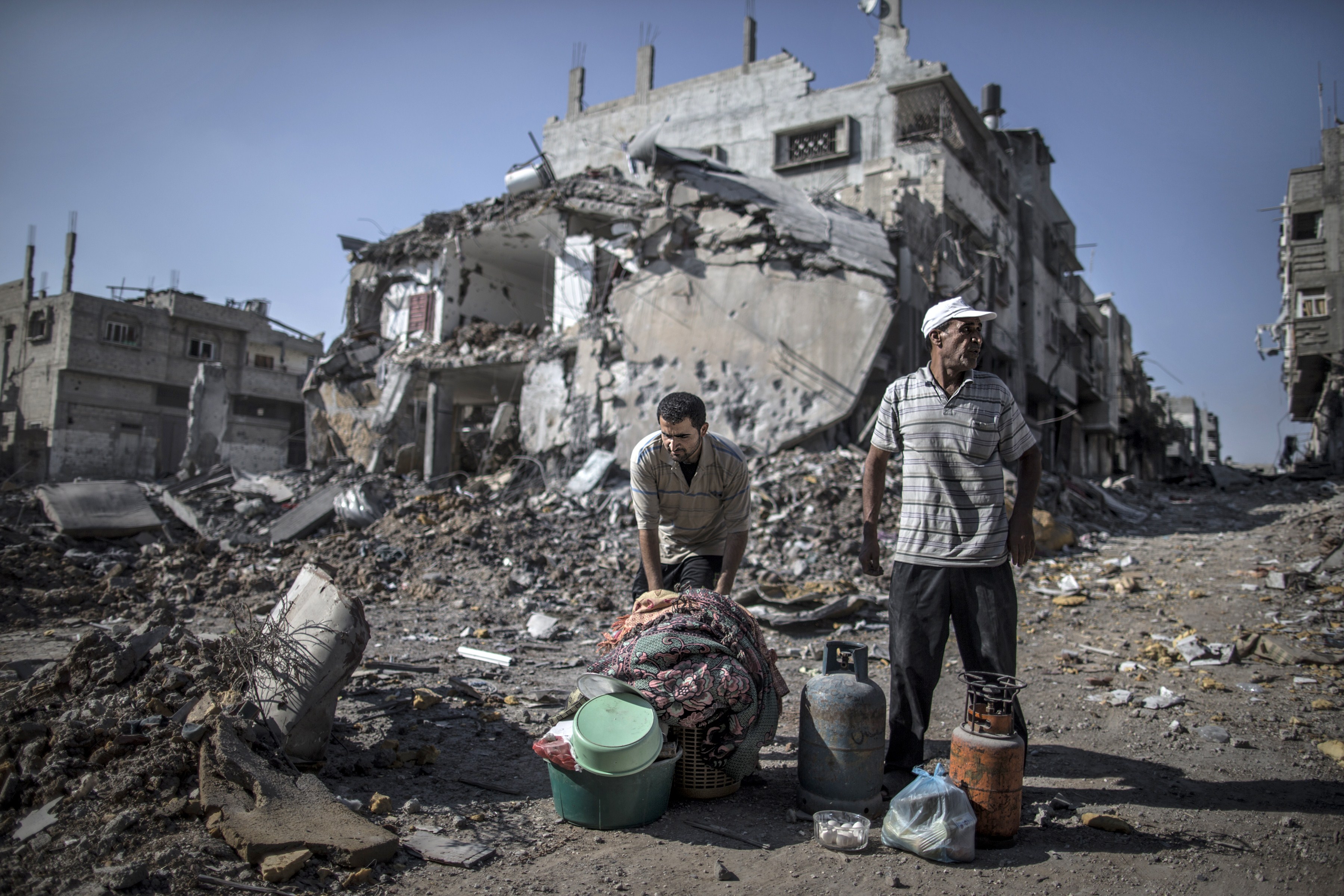 Palestinian men gathered things they found in the rubble of destroyed buildings in a Gaza City district.