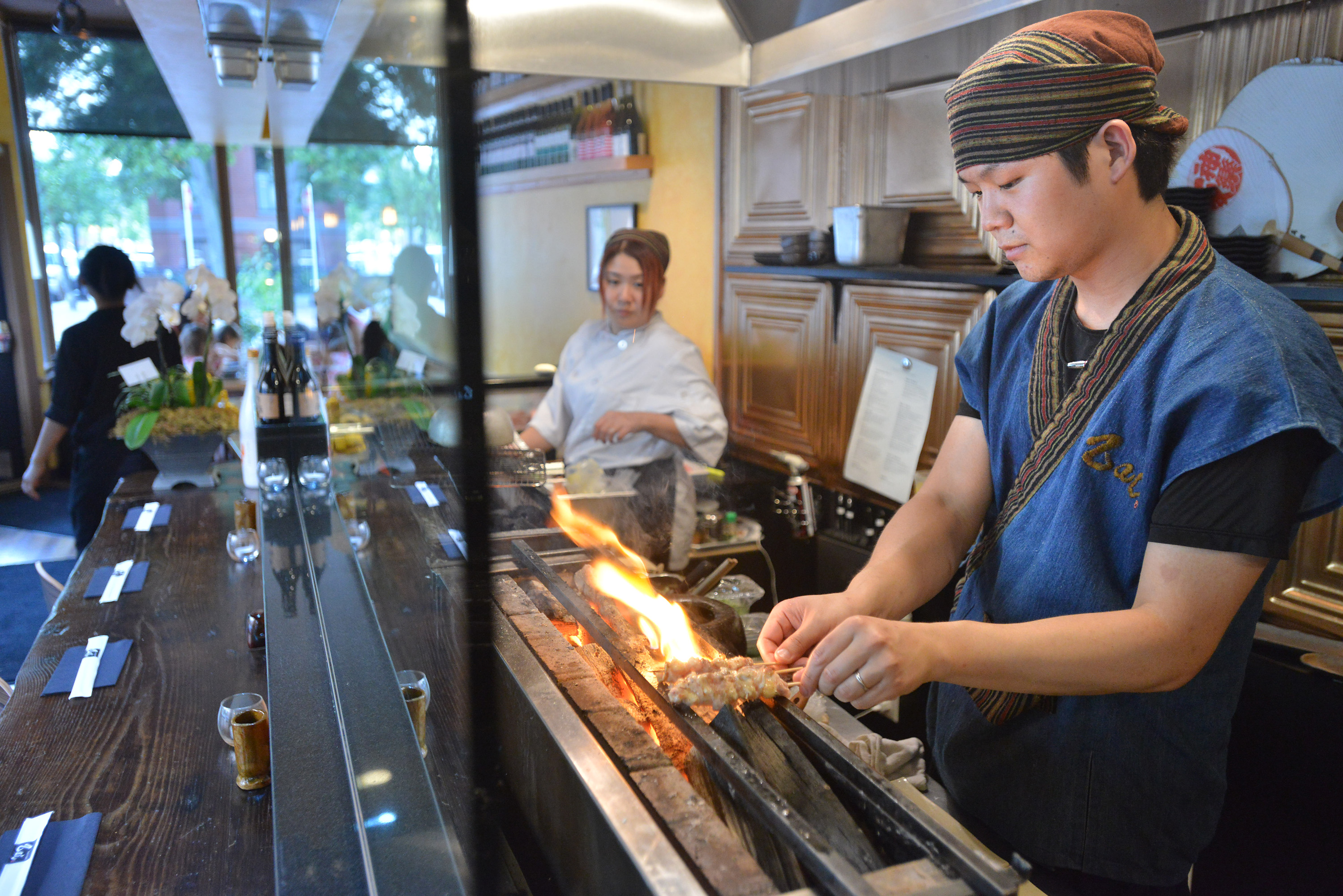 Executive Chef Sho Inoue cooks an order on the special charcoal grill Yakitori Zai in the South End.