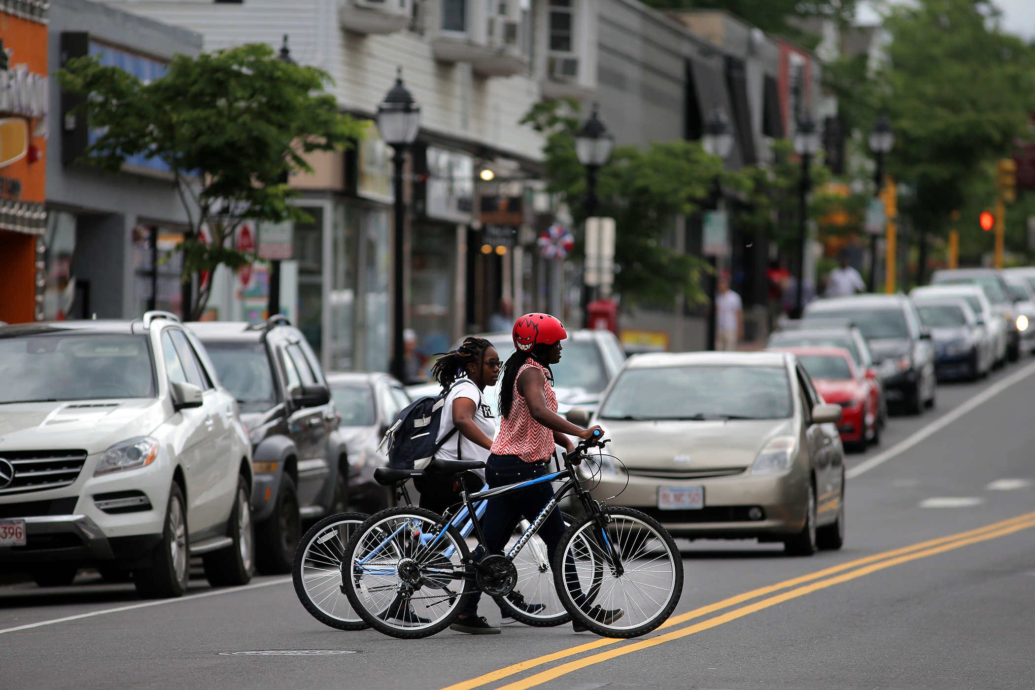 Girls cross Moody Street in Waltham with their bicycles.