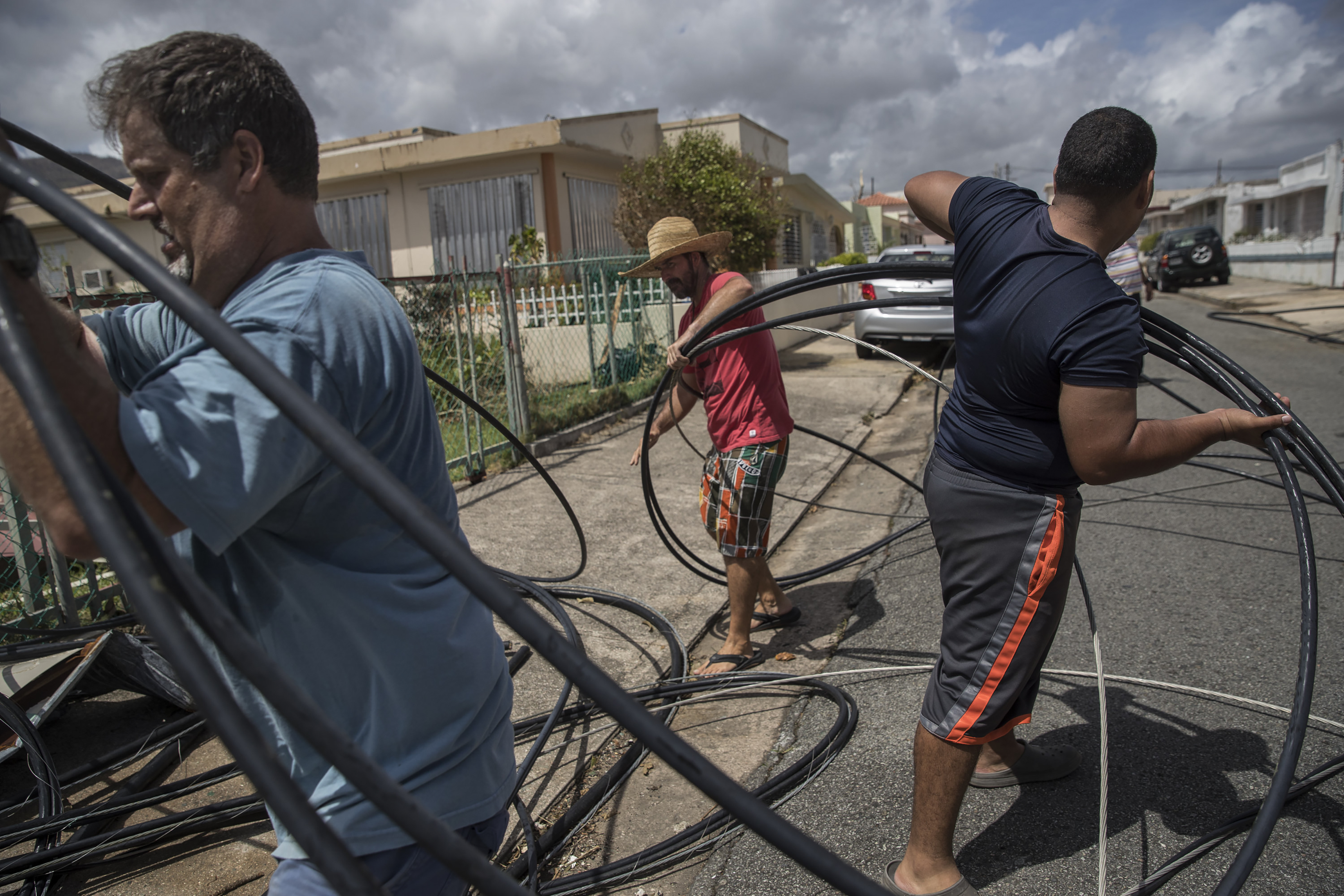 Neighbors David Riefkohl (left), Charles Yates (center) and Jose Nieve (right) cleared downed power lines from their block in Yabucoa, Puerto Rico on Sunday.