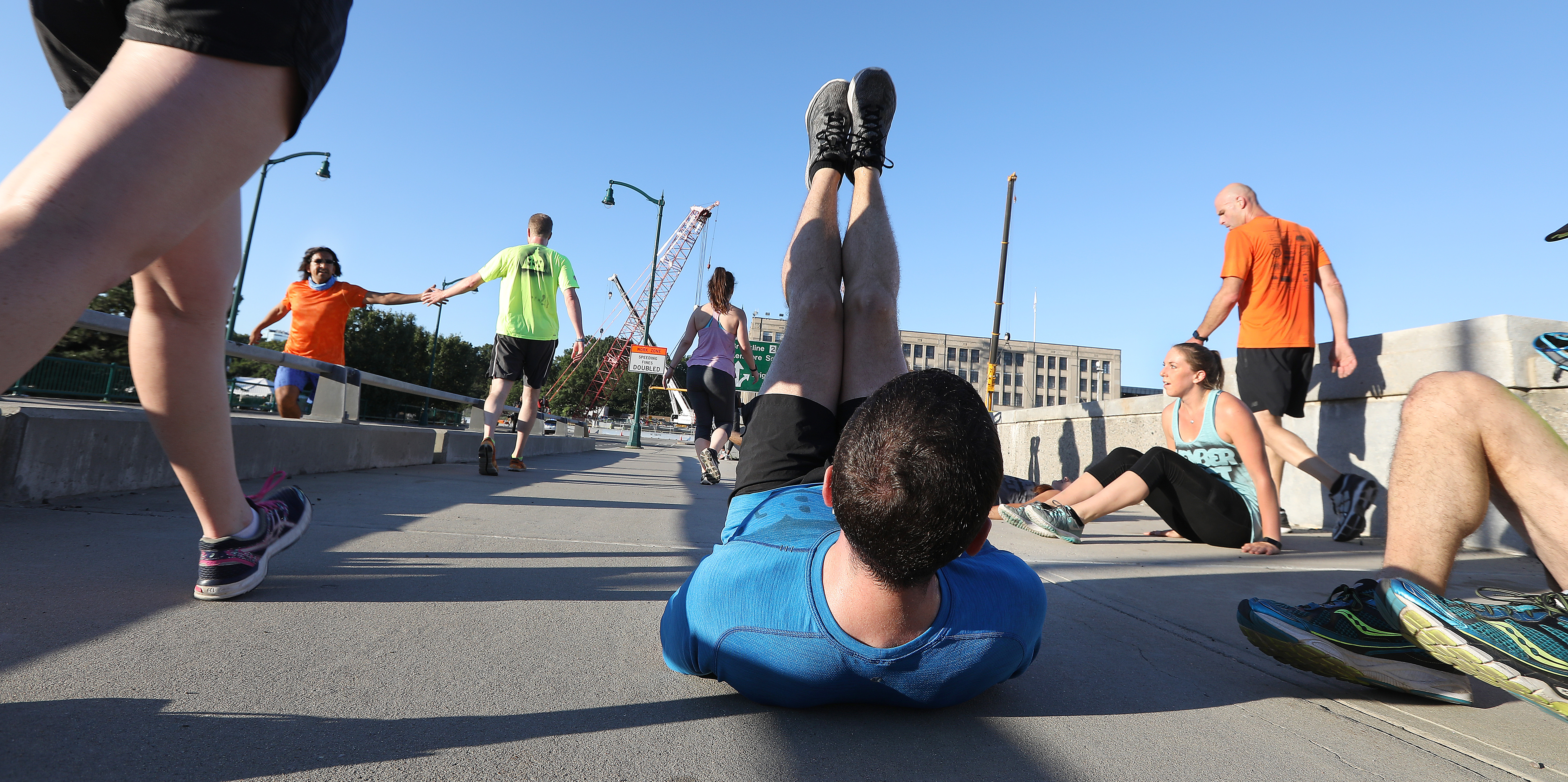 With construction cranes as a backdrop, a group took part in a circuit training session on the closed Boston University Bridge.