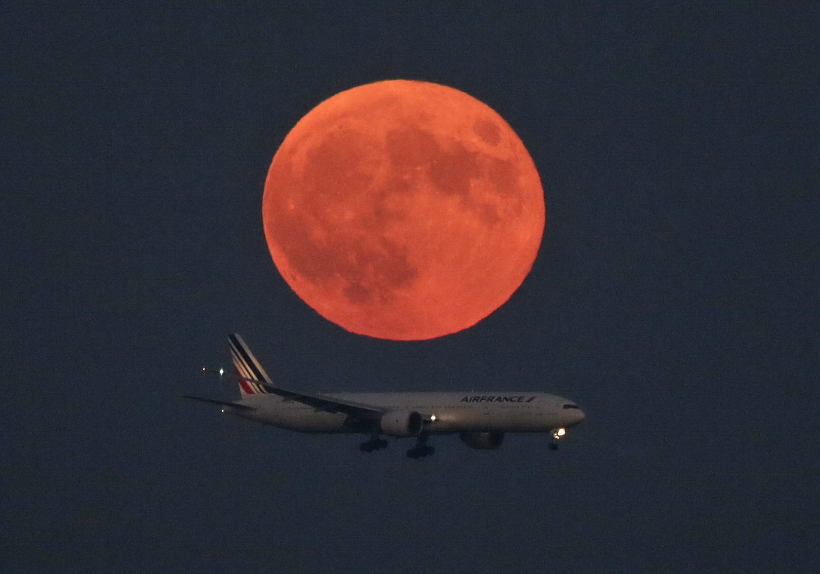 An Air France jetliner apprached the runway at Tokyo International Airport as the supermoon glowed in the background.