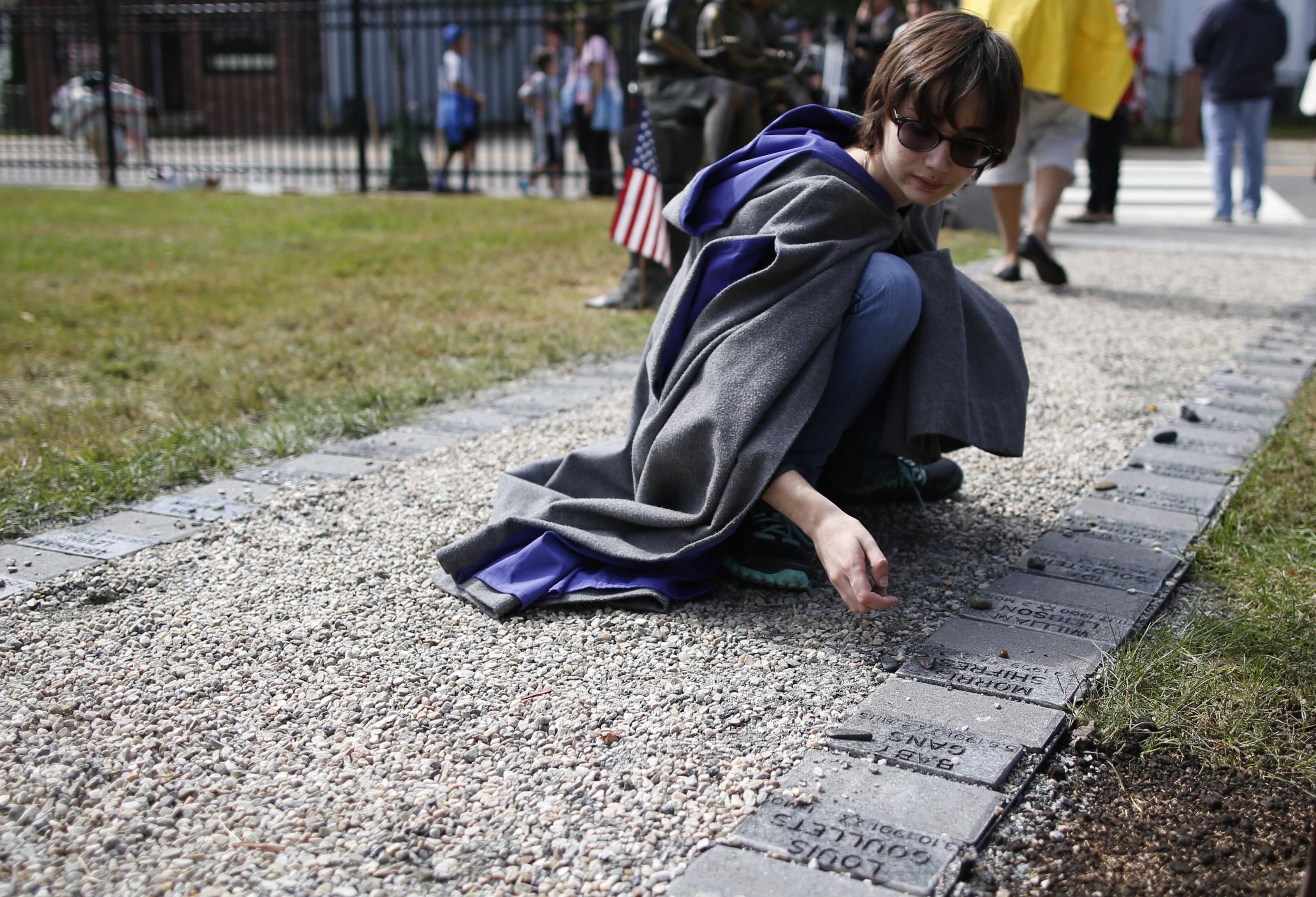 Emma Bibbins, 15, of Medford, placed a stone atop a marker bearing a child’s name; people entered the grounds; and a stone commemorated a baby’s short life .