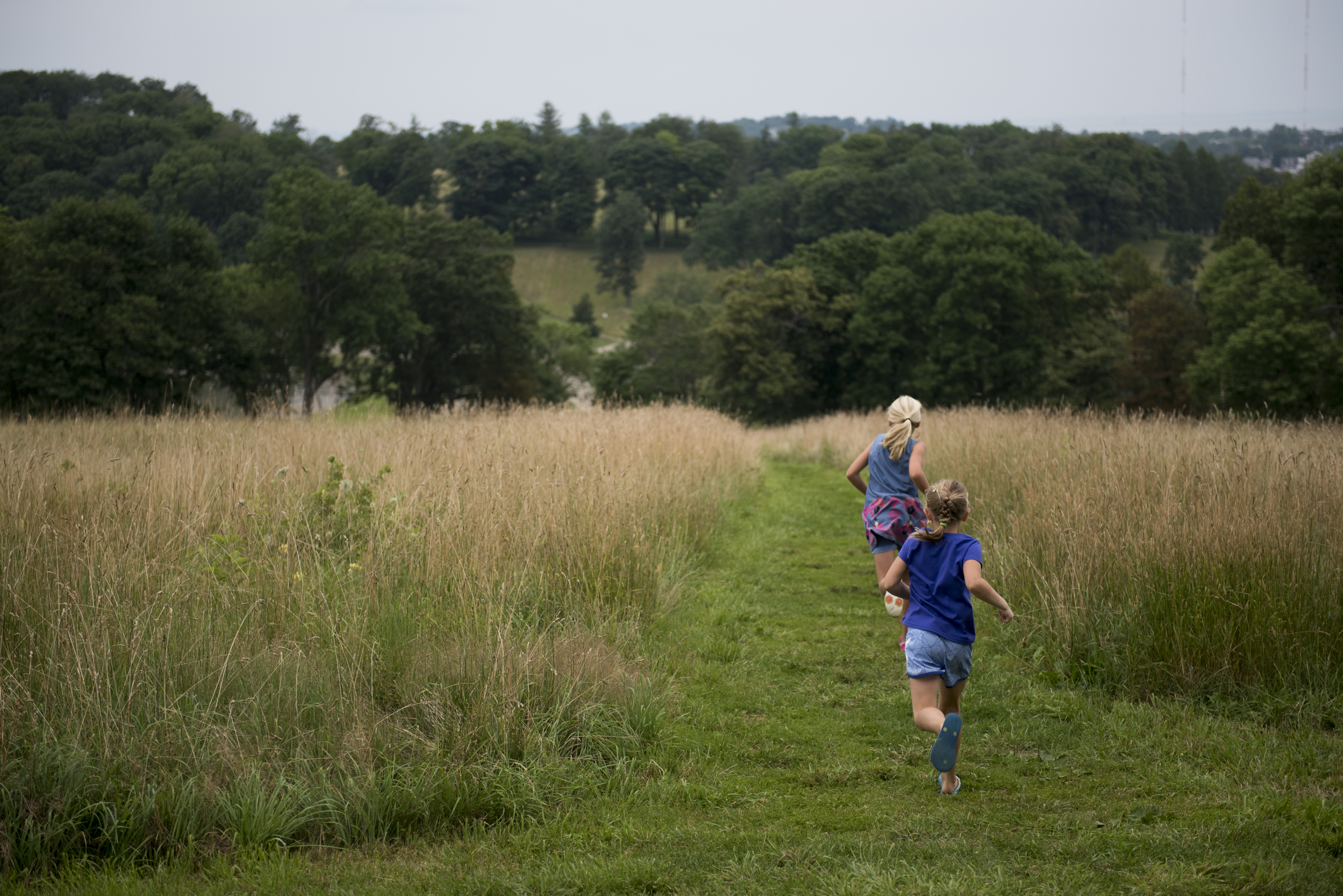 Lauren Armstrong and Rachel Oliwa run down a mowed path during the camping event.