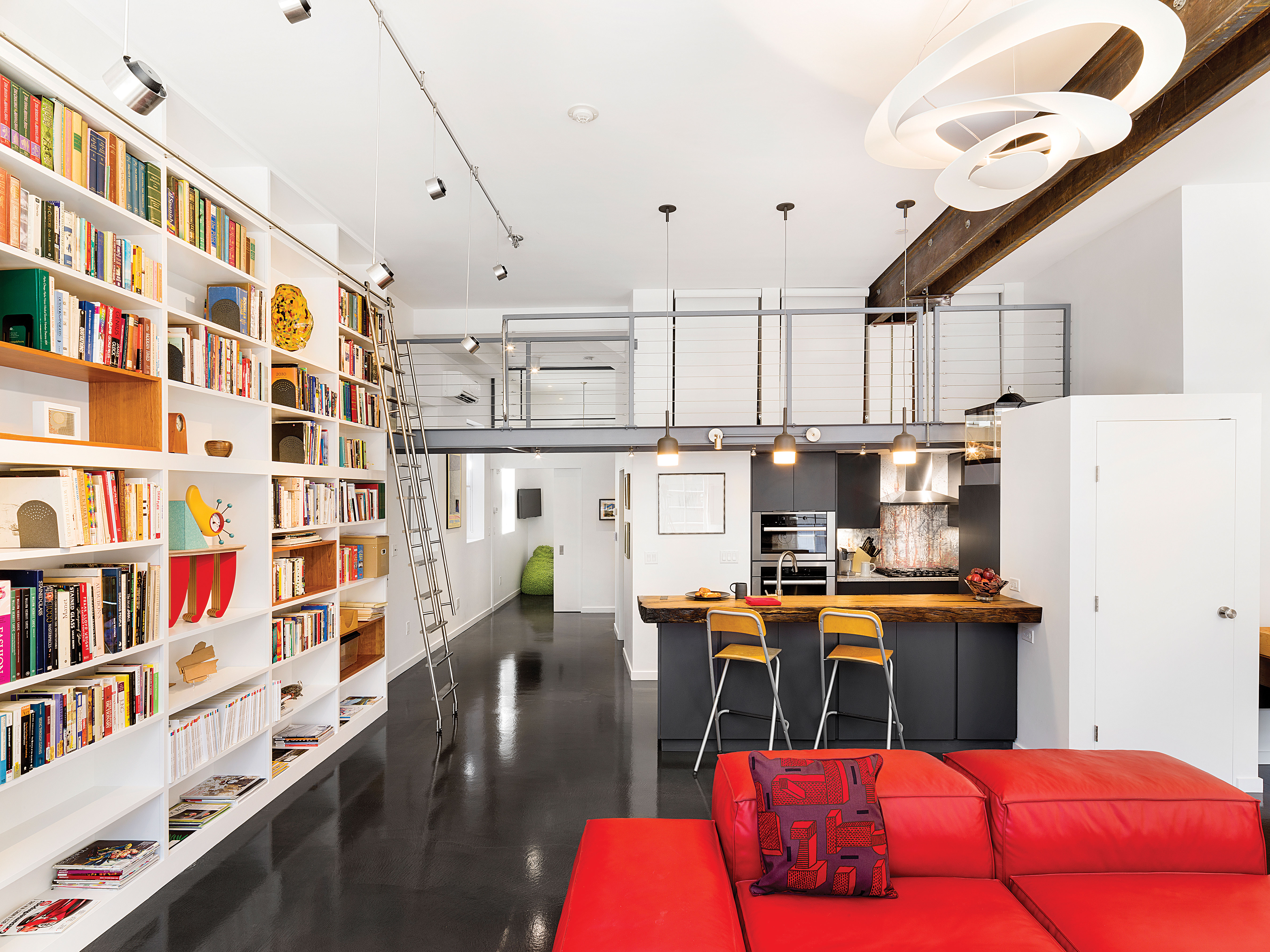 Homeowner Susan Emmerson chose the furniture herself, starting with the red modular sofa by Living Divani from Casa Design in the South End, from which she also purchased the Andreu World bar stools. Architect Cindy Larson worked with Wolfer’s to choose suspended track lighting with a mix of short and long stems to evenly light the bookcase.
