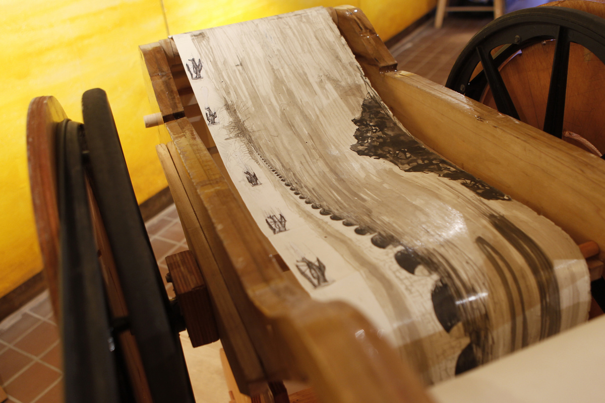Visitors view the work by cranking a large wooden spool.