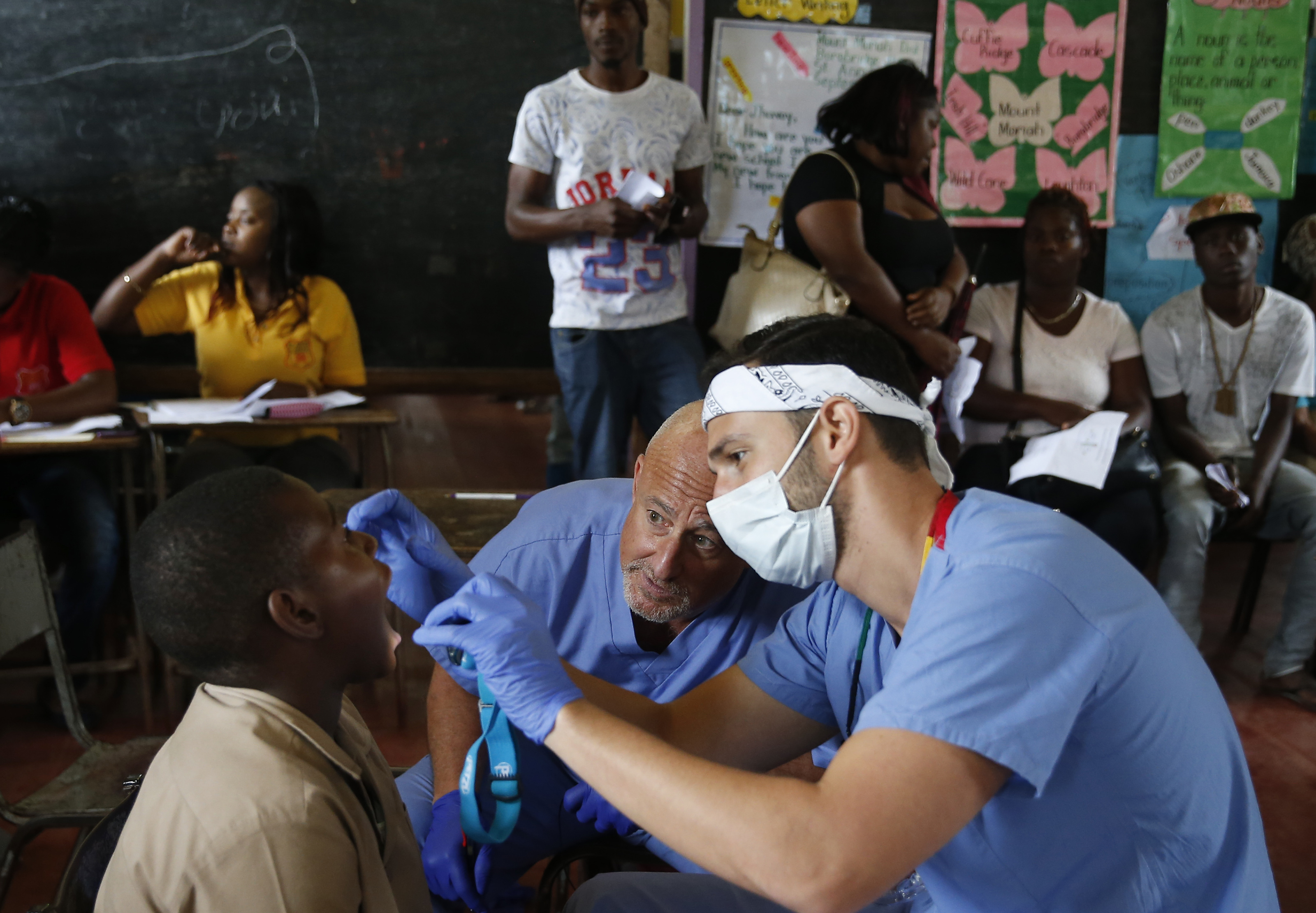 Tufts dental student Michael Golub had his father, orthodontist Dr. Jon Golub, lean in to give him an opinion on a child's tooth as he screened patients upon arrival to the clinic.