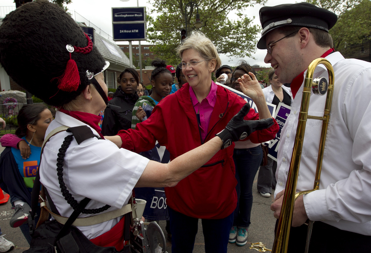 Elizabeth Warren greeted Providence Brass Band members Barbara Kuzdzol (left) and Dan Gabel, before marching in the Dorchester Day Parade.