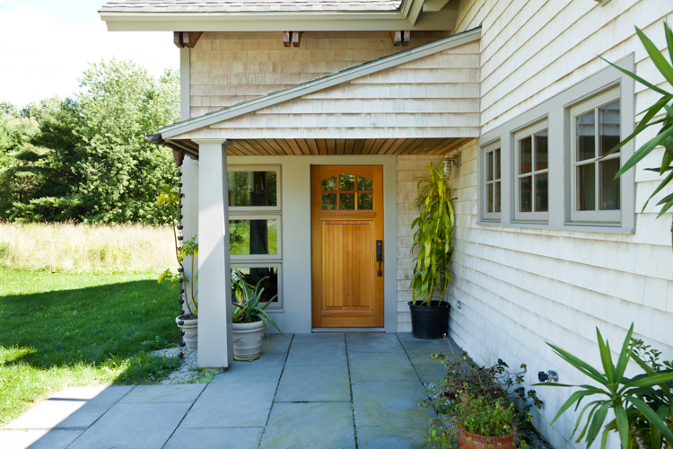A welcoming entrance in New England has a generous covered landing for those arriving and large sidelight that allows a seated homeowner to see outside. “The Accessible Home” (The Taunton Press)