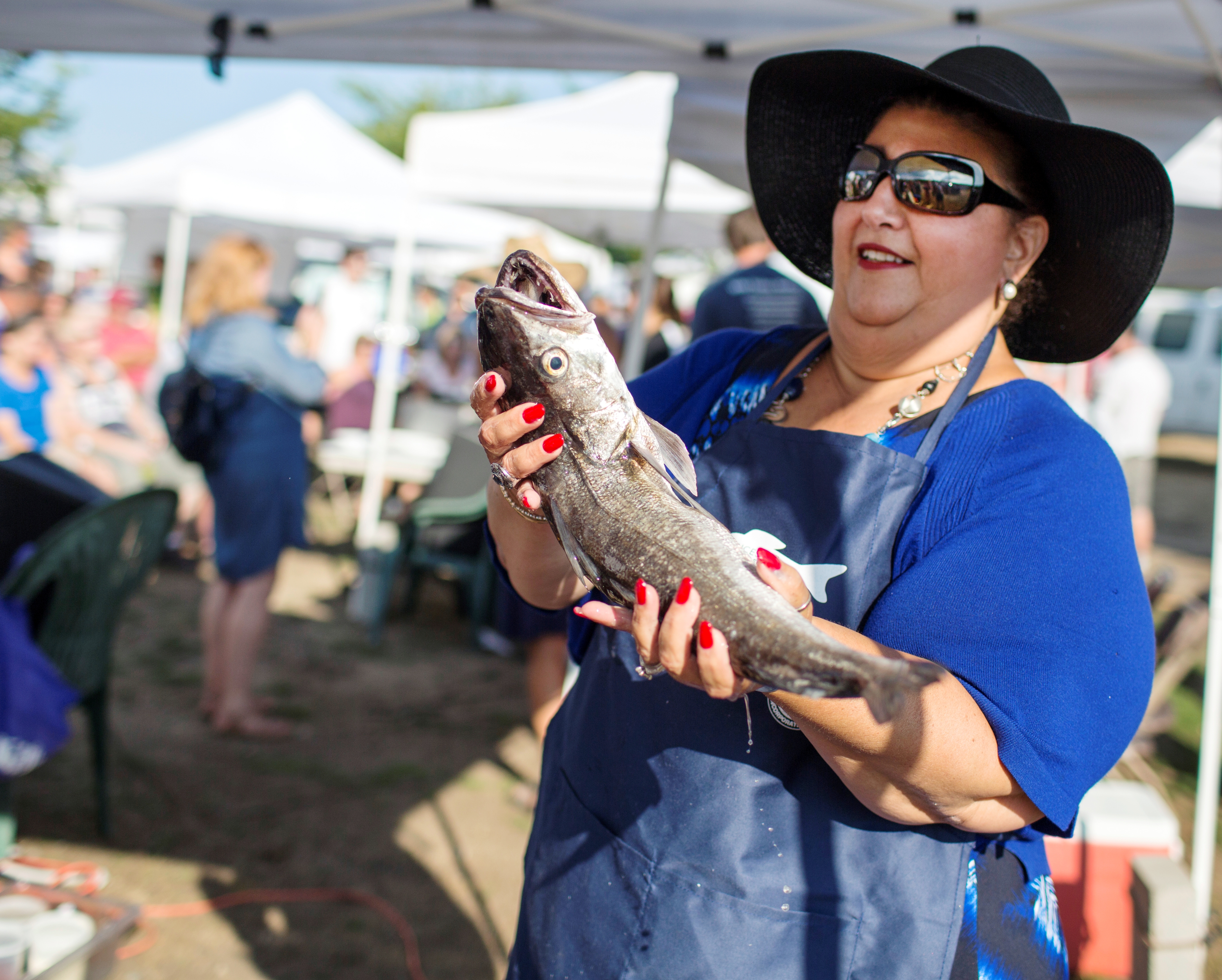 Mayor Sefatia Romeo Theken, who comes from a fishing family, holds up a whiting caught off Gloucester at the Seafood Throwdown in August.