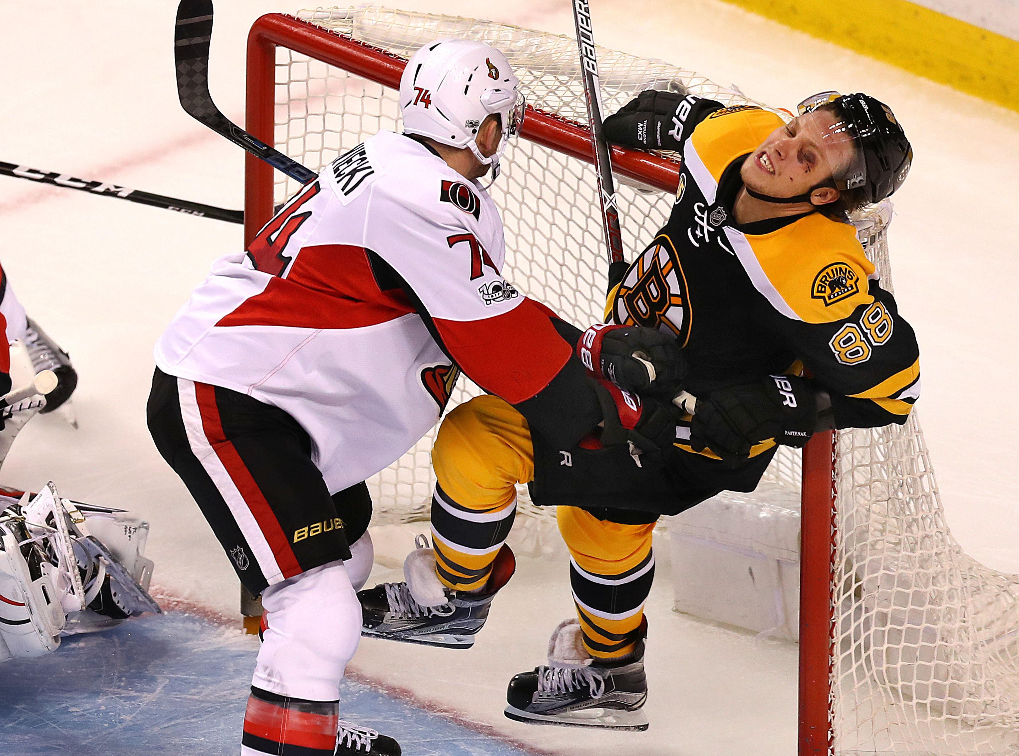 Bruin David Pastrnak gets pushed into the crossbar by Ottawa’s Mark Borowiecki.