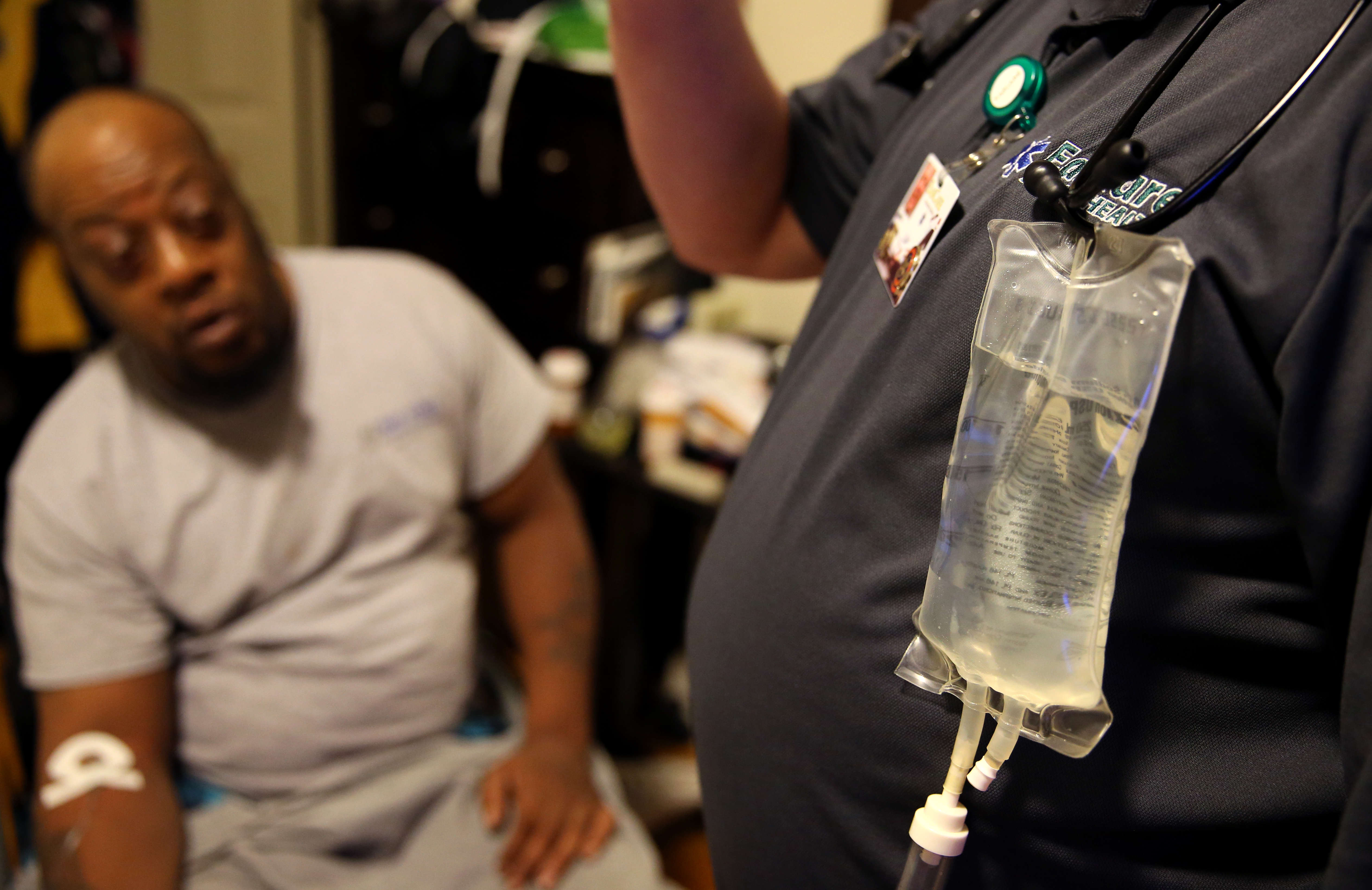 Paramedic Matthew Michaud (right) used an IV to treat an infection during a home visit with Jamal Lee (left) in Quincy.