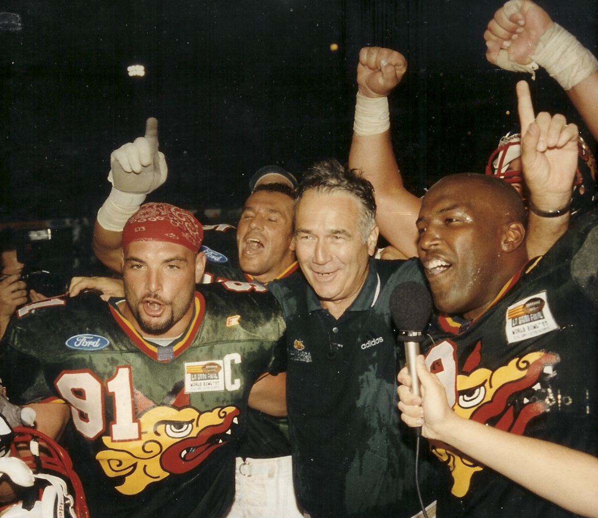 Naposki (left) played for four years in NFL Europe with the Barcelona Dragons under coach Jack Bicknell (center), who called him “everything you wanted in a teammate and a player.’’
