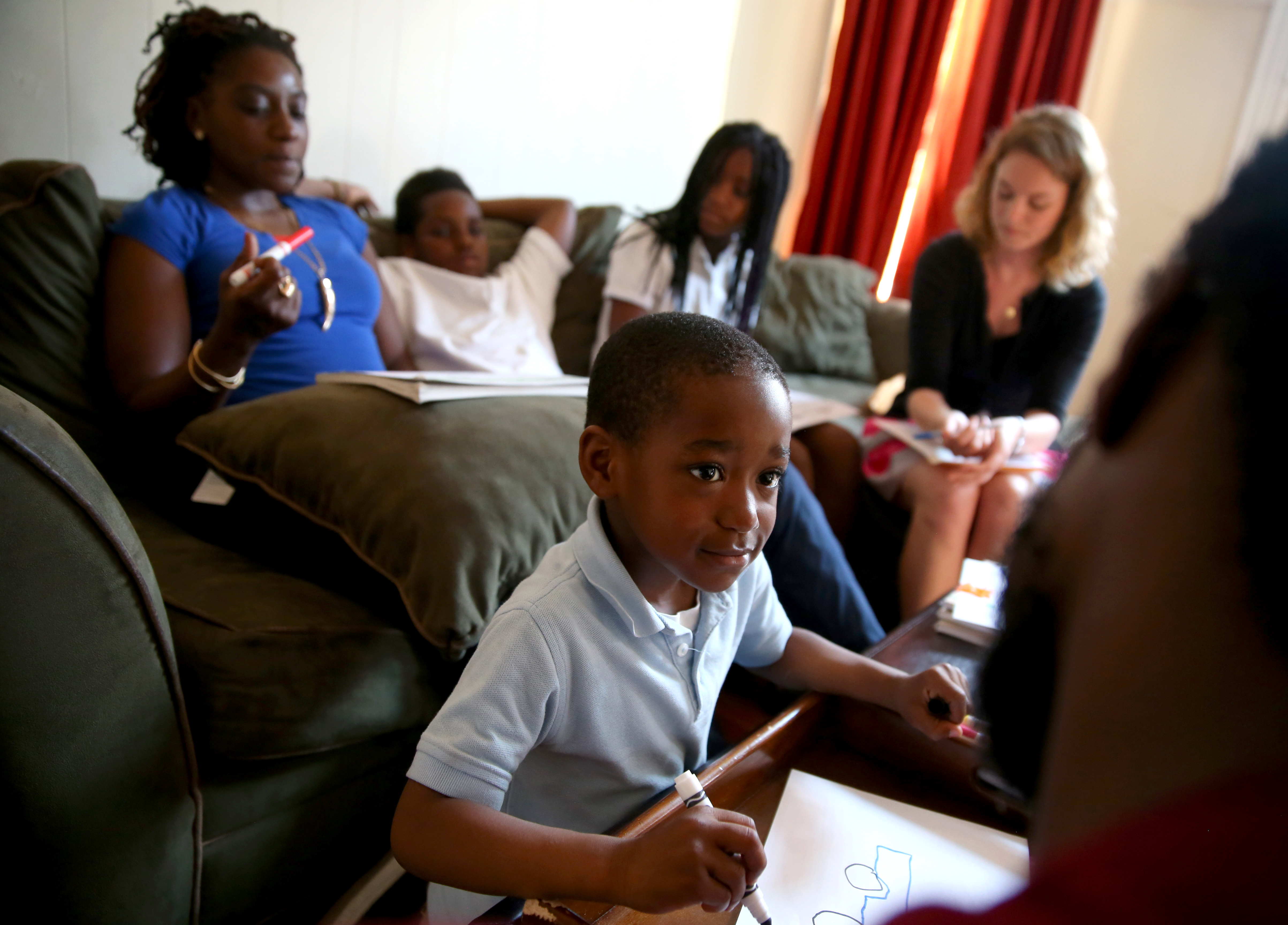 Jah, 5, drew a picture with his father, Shiloh Jackson, as EMPath coordinator Stephanie Brueck (top, far right) worked with other members of the family.