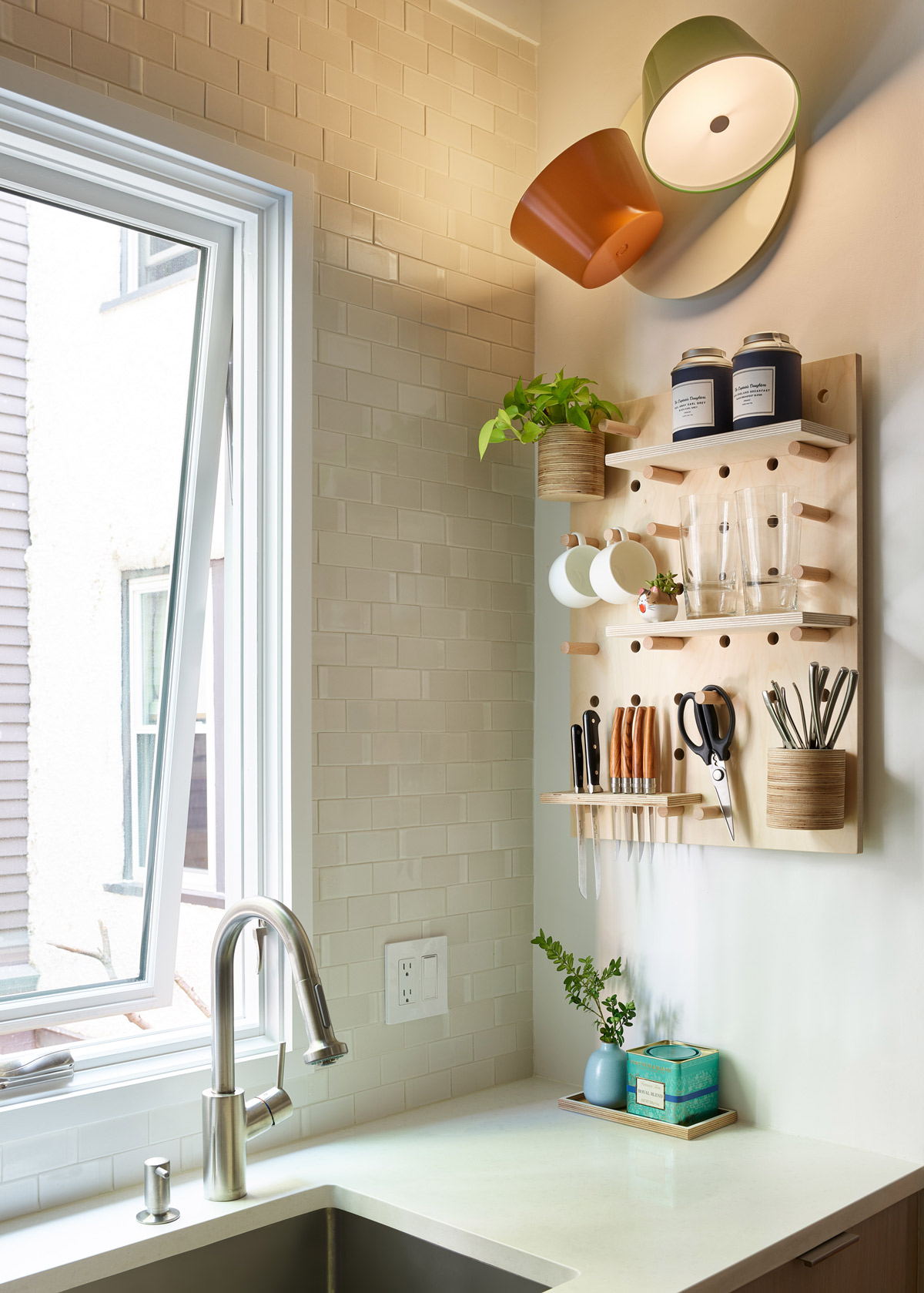 An orange and green wall sconce by Marset hangs above a pegboard by Kreisdesign.
