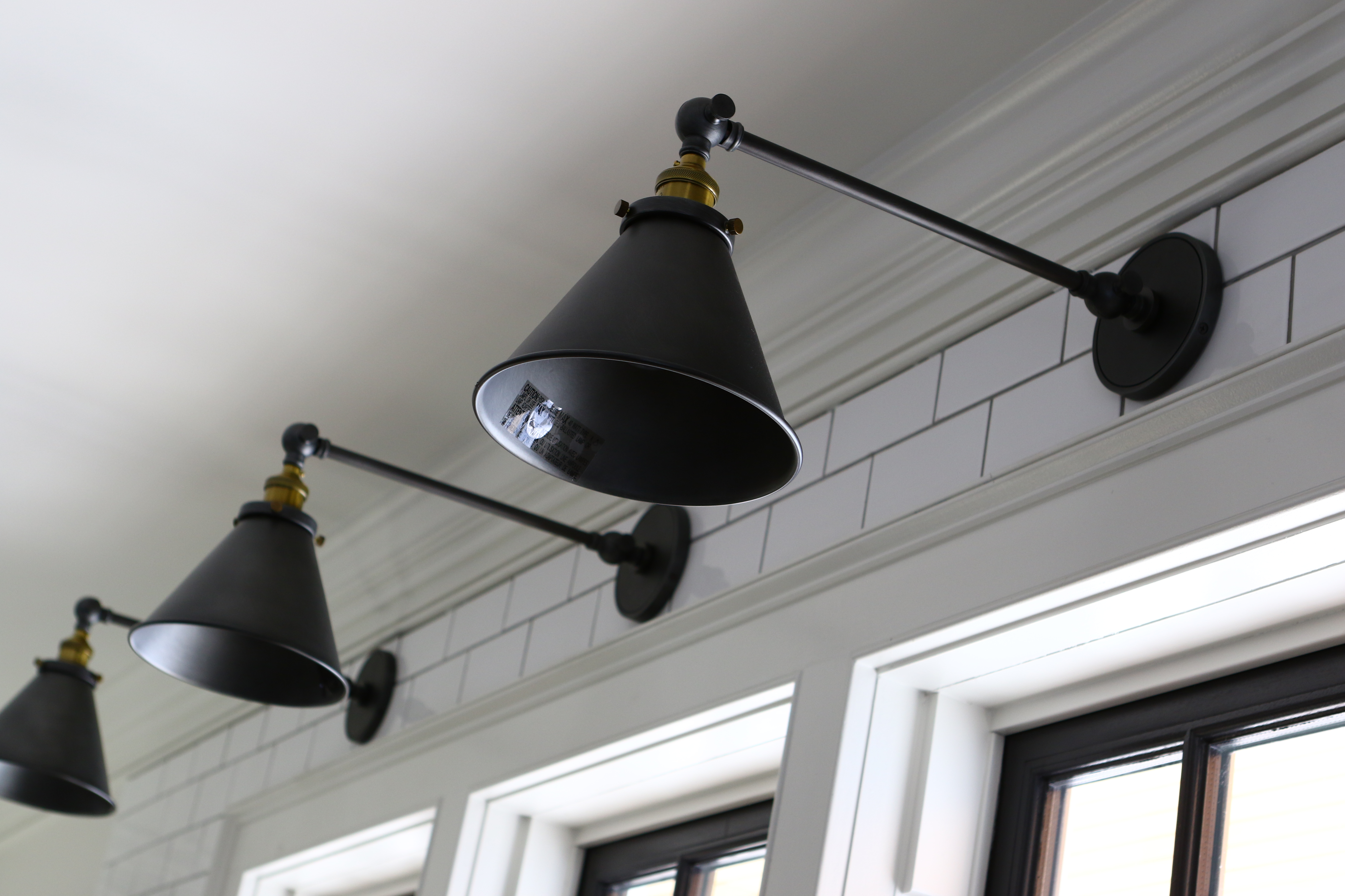 Sconces from RH are perched over windows above the kitchen sink.