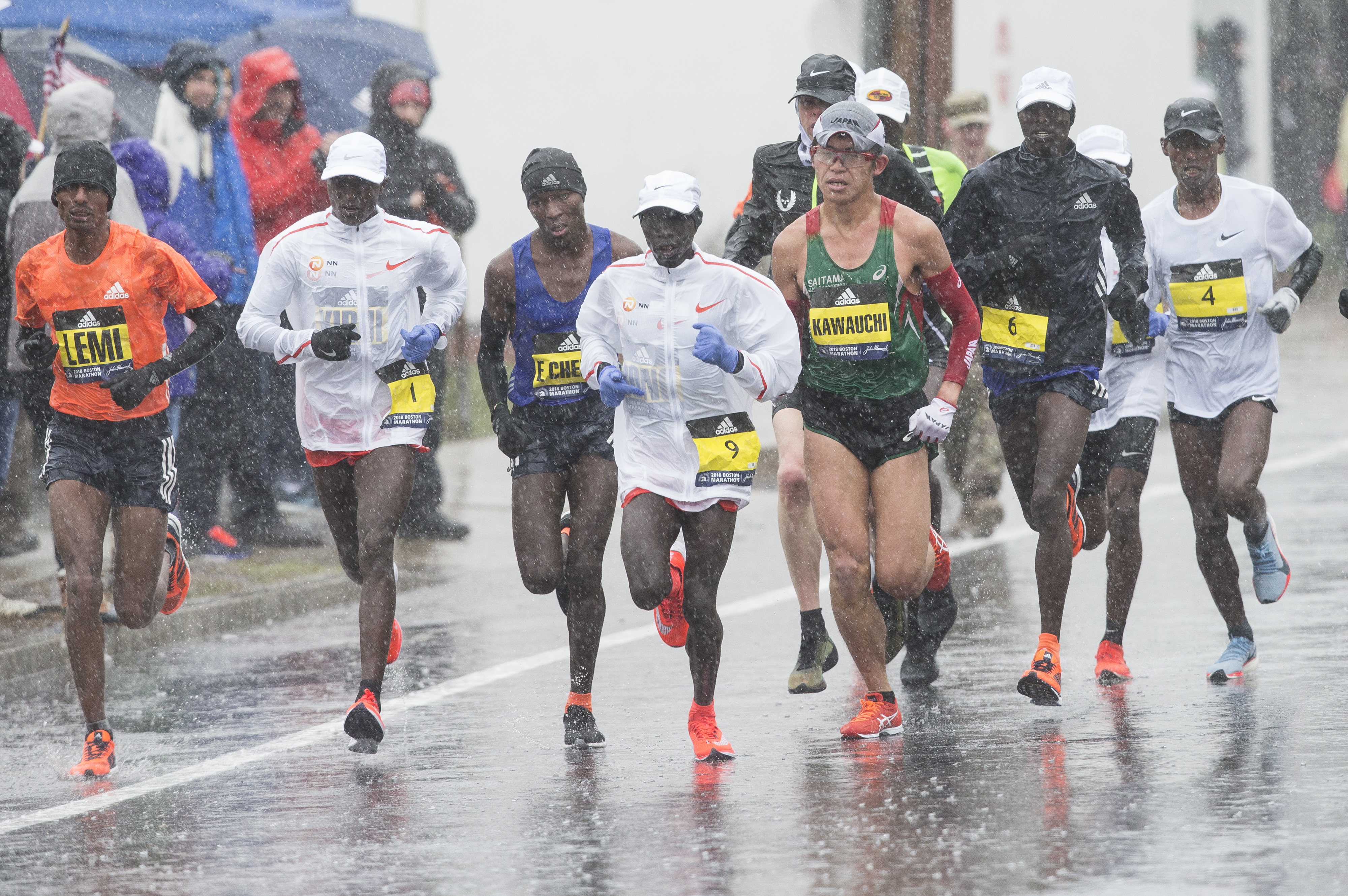 A pack of elite men splashes through Needham on a miserable weather day.