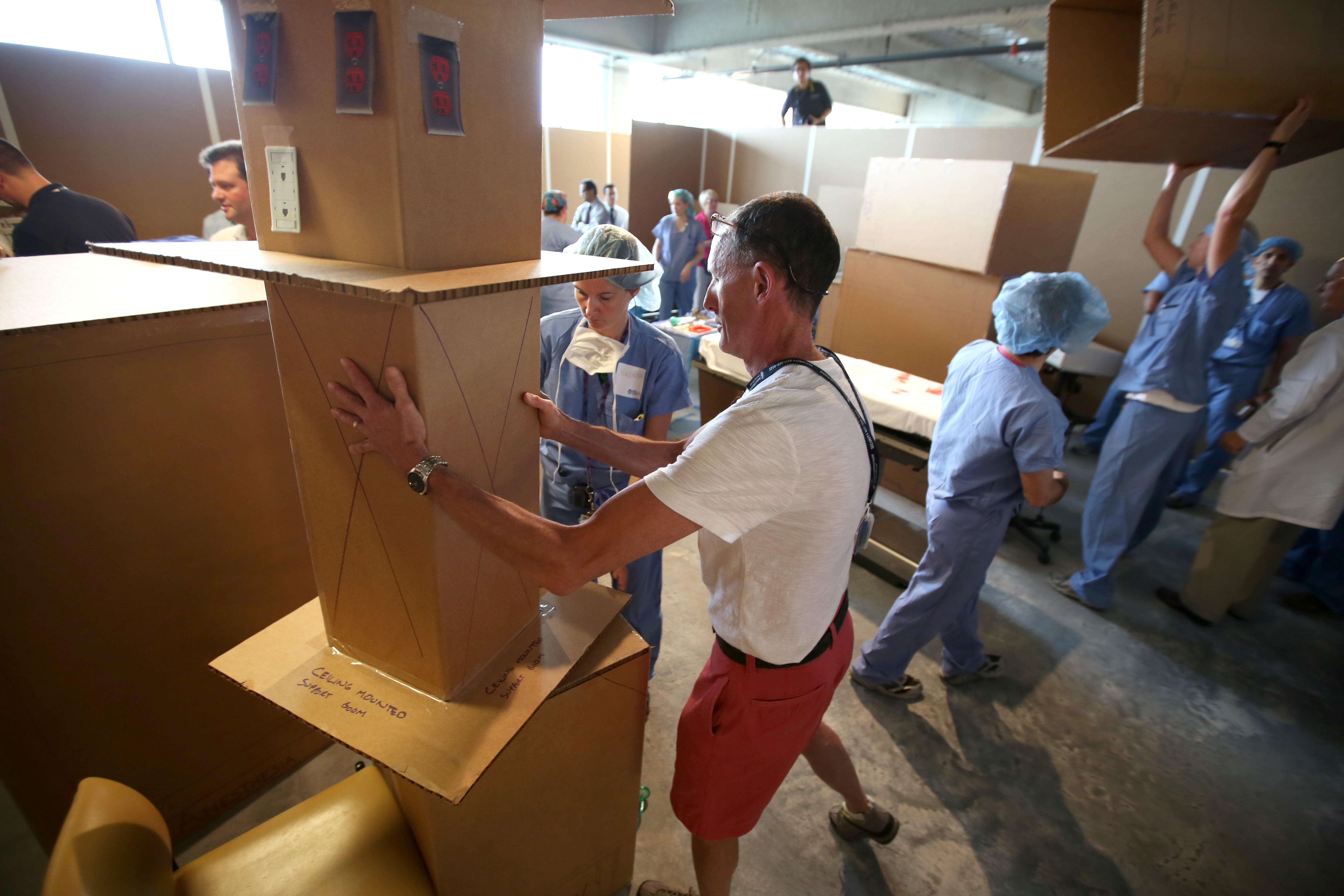 Clinicians reposition sections of the “cardboard city” to find the optimum operating room layout during a mock exercise.