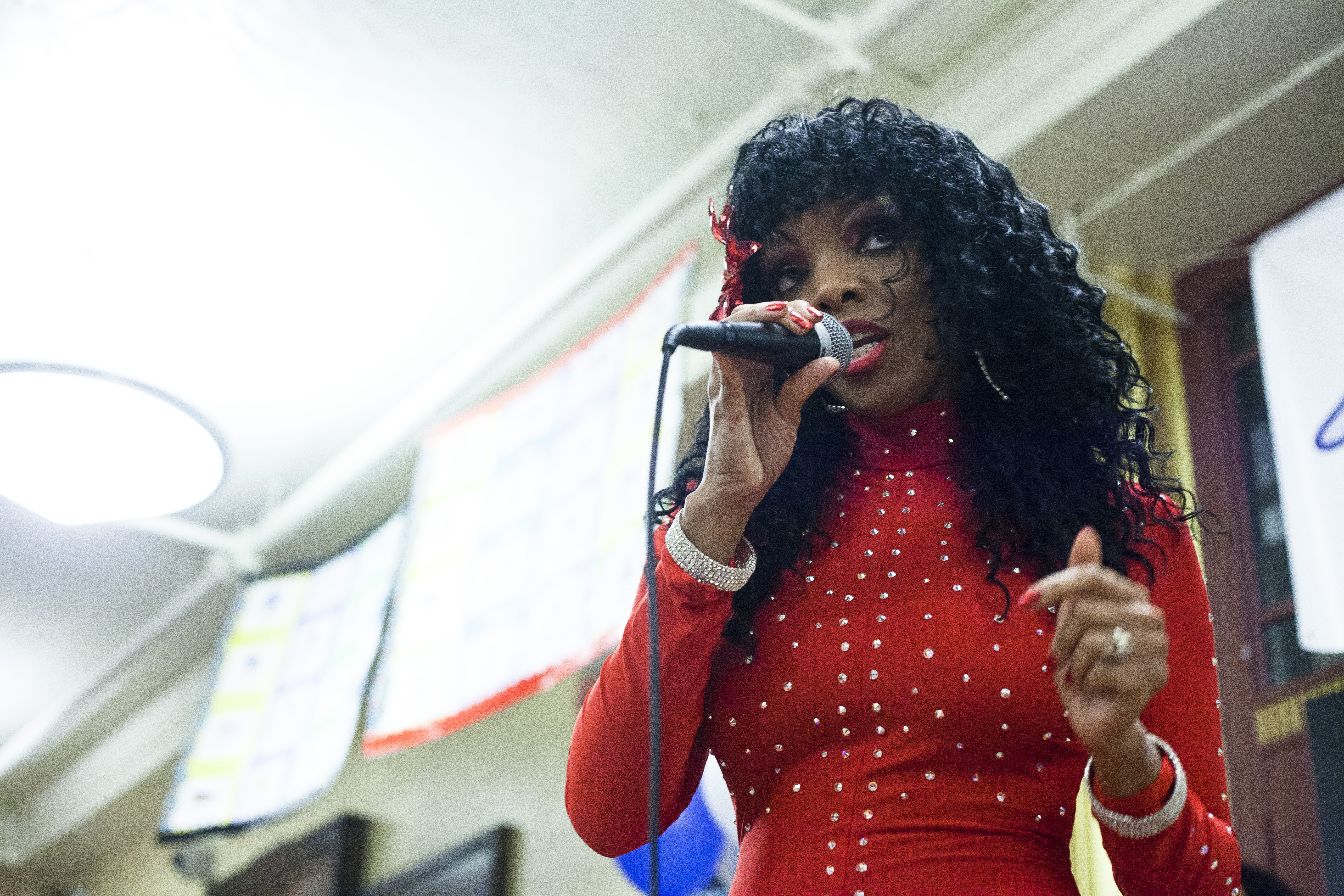 Principal Lindsa McIntyre (in red) hugs a guest and Rainere Martin sings at the Donna Summer mural concert at Jeremiah E. Burke High School.