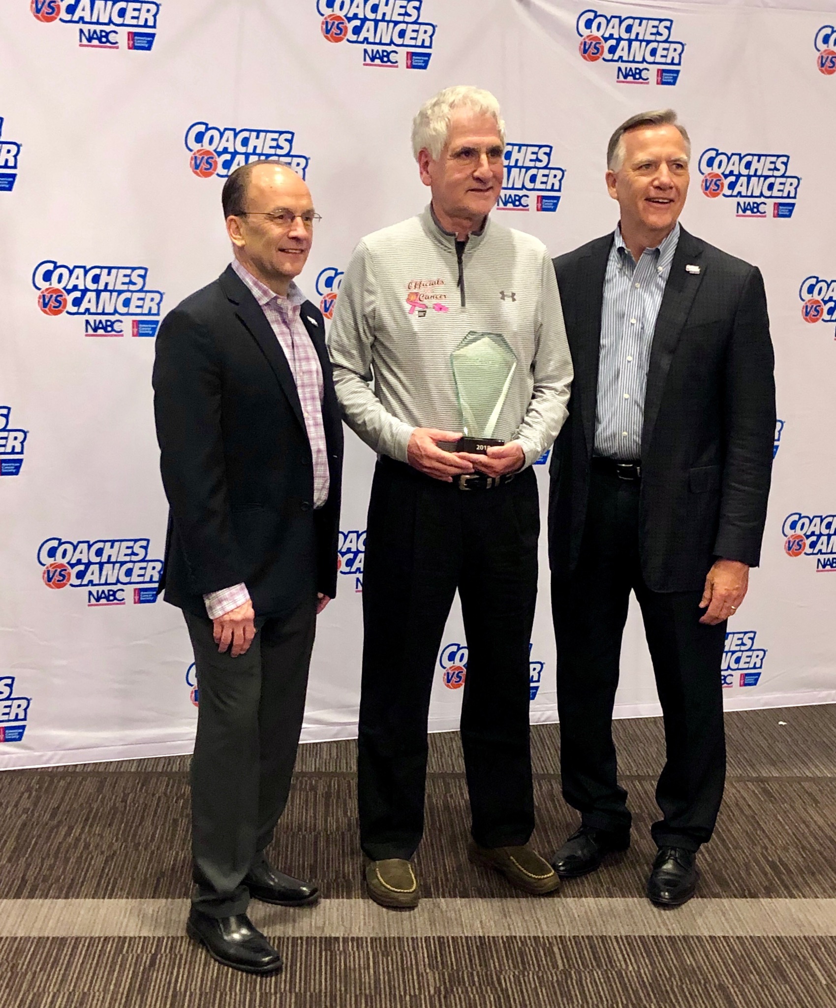Acton’s Lou Levine (center) became the first game official honored by the American Cancer Society with the Champion Award, part of the Coaches vs. Cancer program.