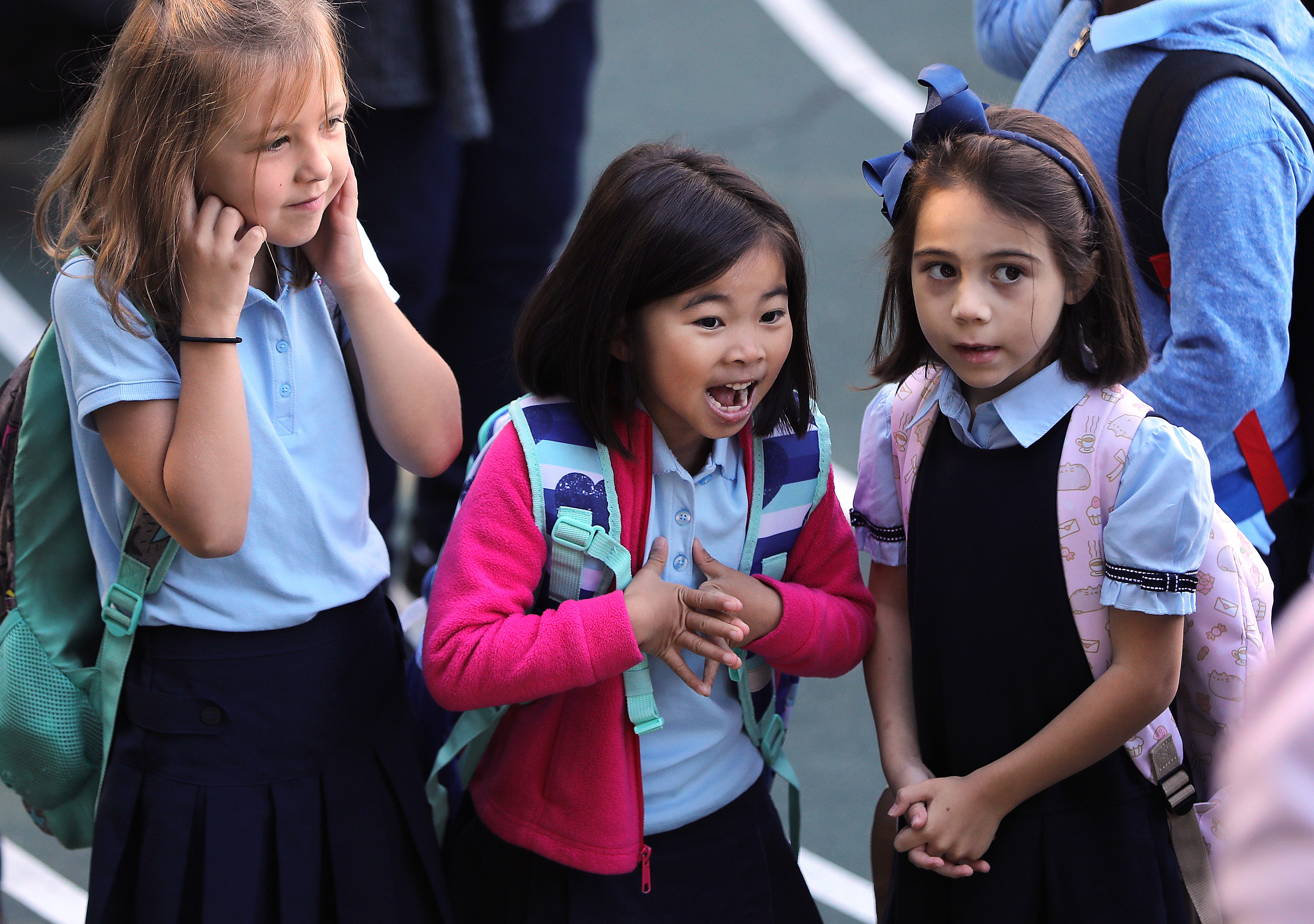 From left, Lily Boissaye, Felicia Wong, and Anabelle Quinones Fontana waited to walk into school to start first grade. Across Boston, families waited for hours to land a spot at one of the city’s 125 schools.