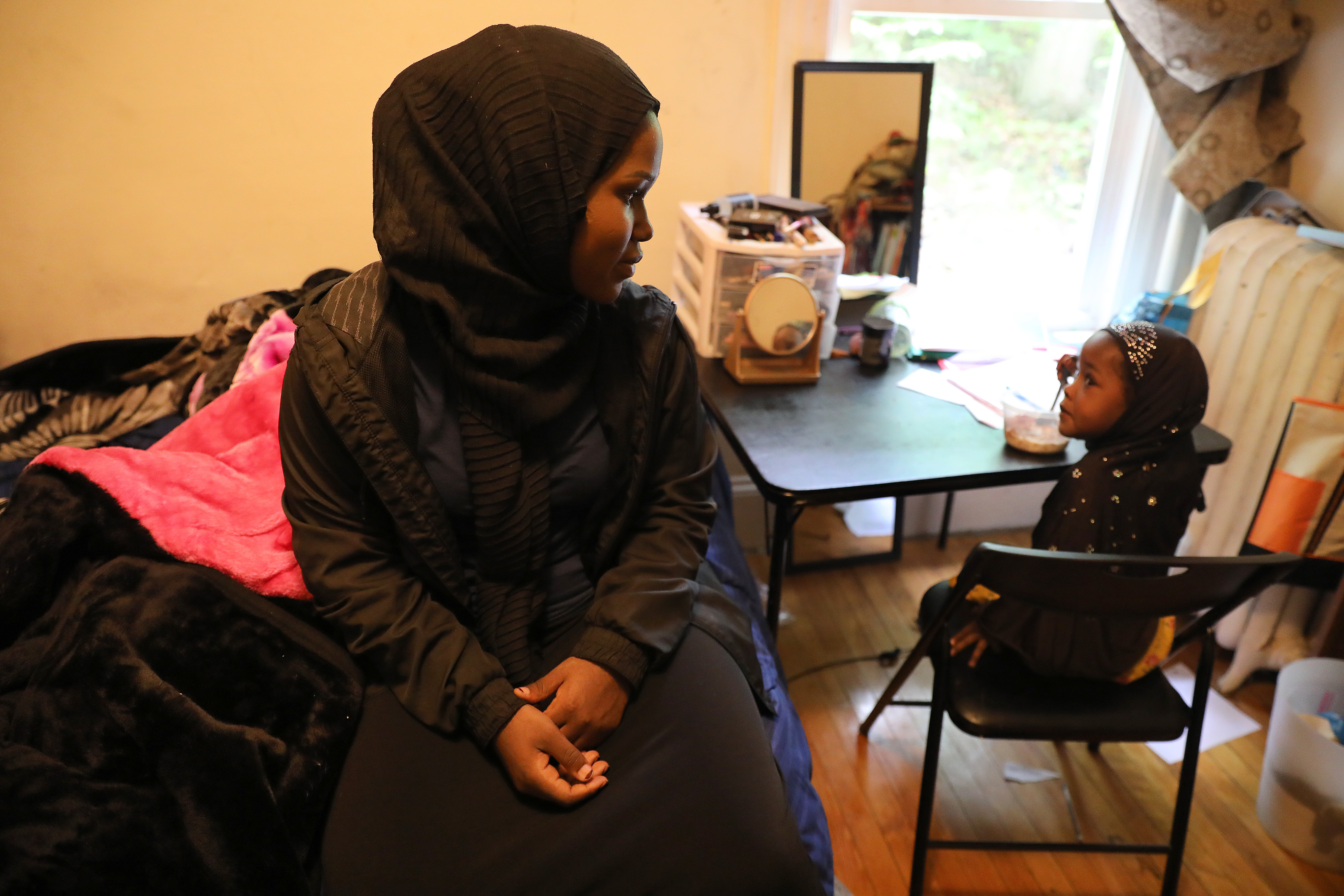 Shukri Abdirahman a graduate of the Edward Little High School got ready for work the morning after pulling a double shift, in Lewiston. She sat with her 3-year-old niece Iqra who has her breakfast.