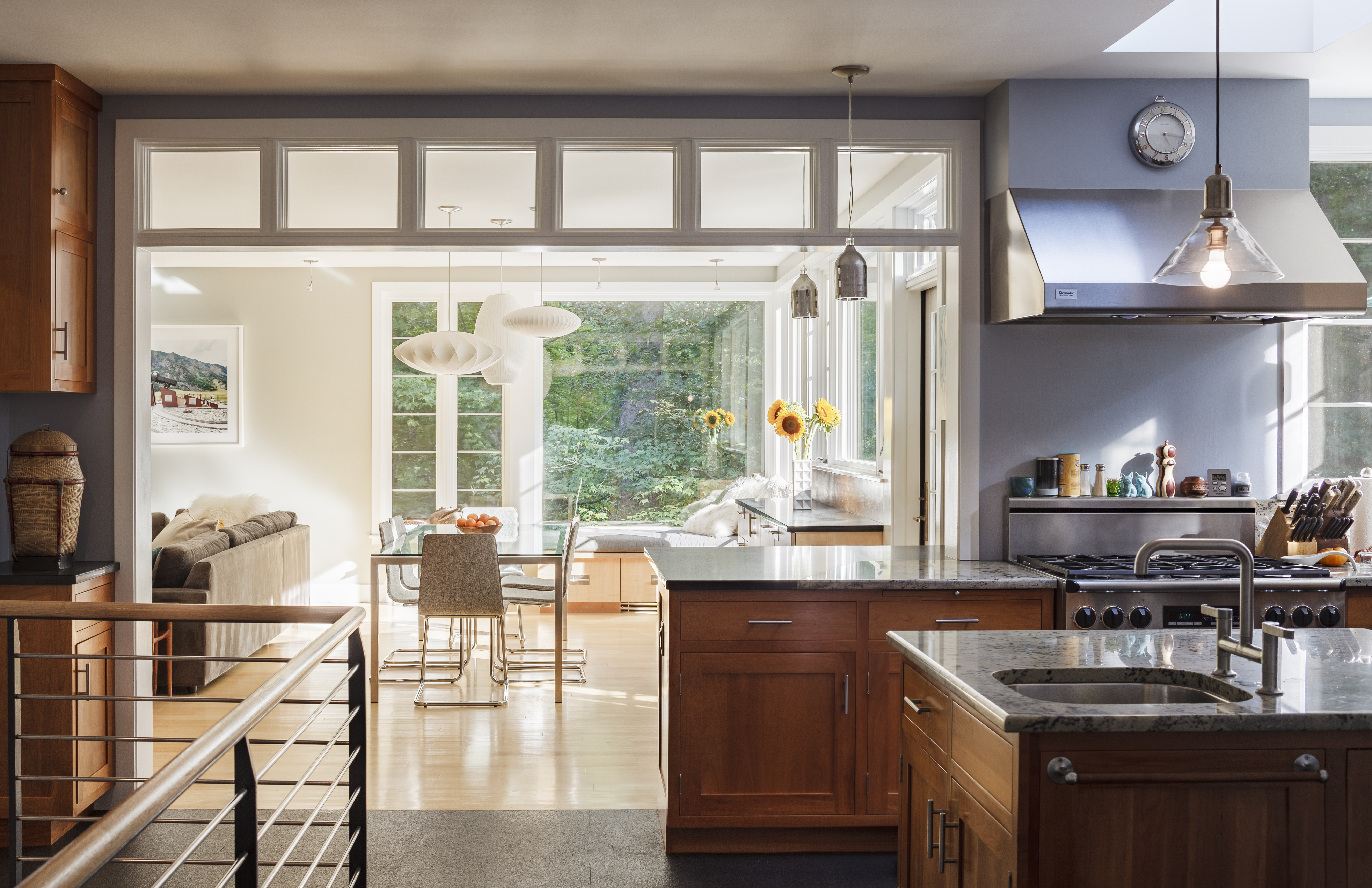 In the kitchen, cabinetry came down to expose the stairs to the playroom. The rail echoes the design of the outdoor deck rails; the floor tiles are made from recycled rubber tires.