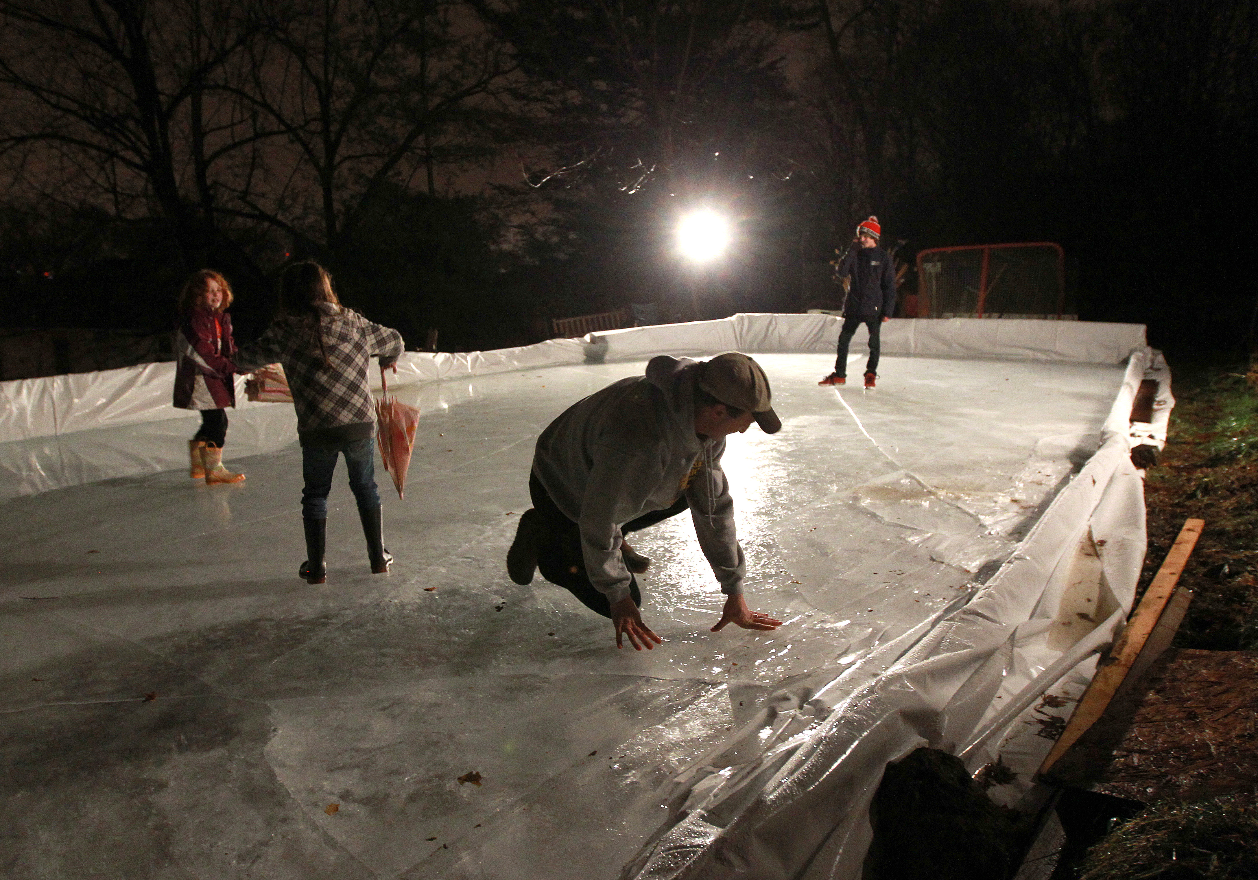 In January of 2012, Jon Frankel of Brookline (kneeling third from the left) checked out the condition of his backyard rink as daughters Mia and Wendy and son Adam slip and slide on the thin ice.