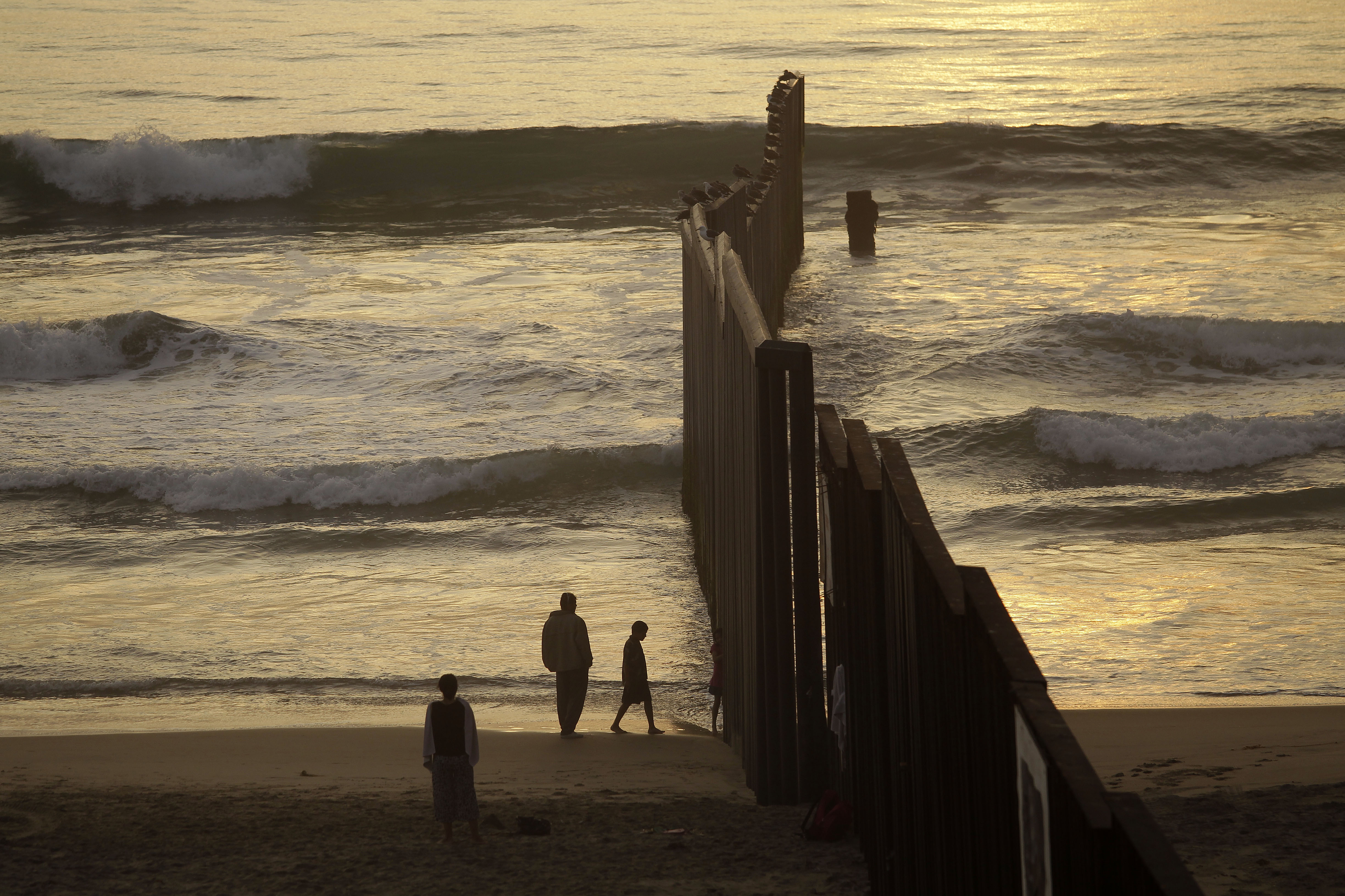 People at a beach next to the border fence separating Mexico from the US in Tijuana, Mexico.