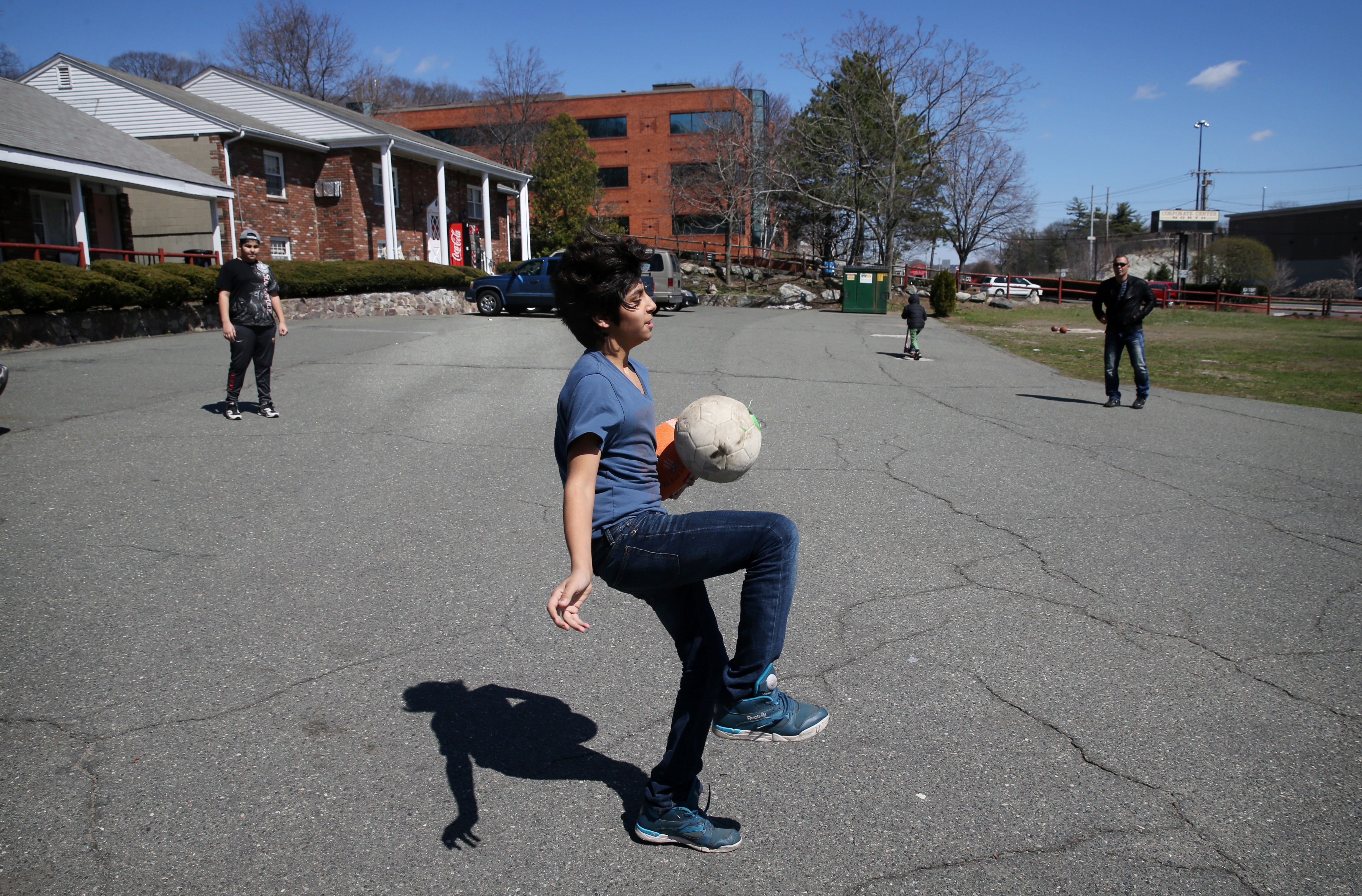Abdul Wahab Al Rubaye plays soccer with his family outside their room at the Colonial Traveler Inn in Saugus.