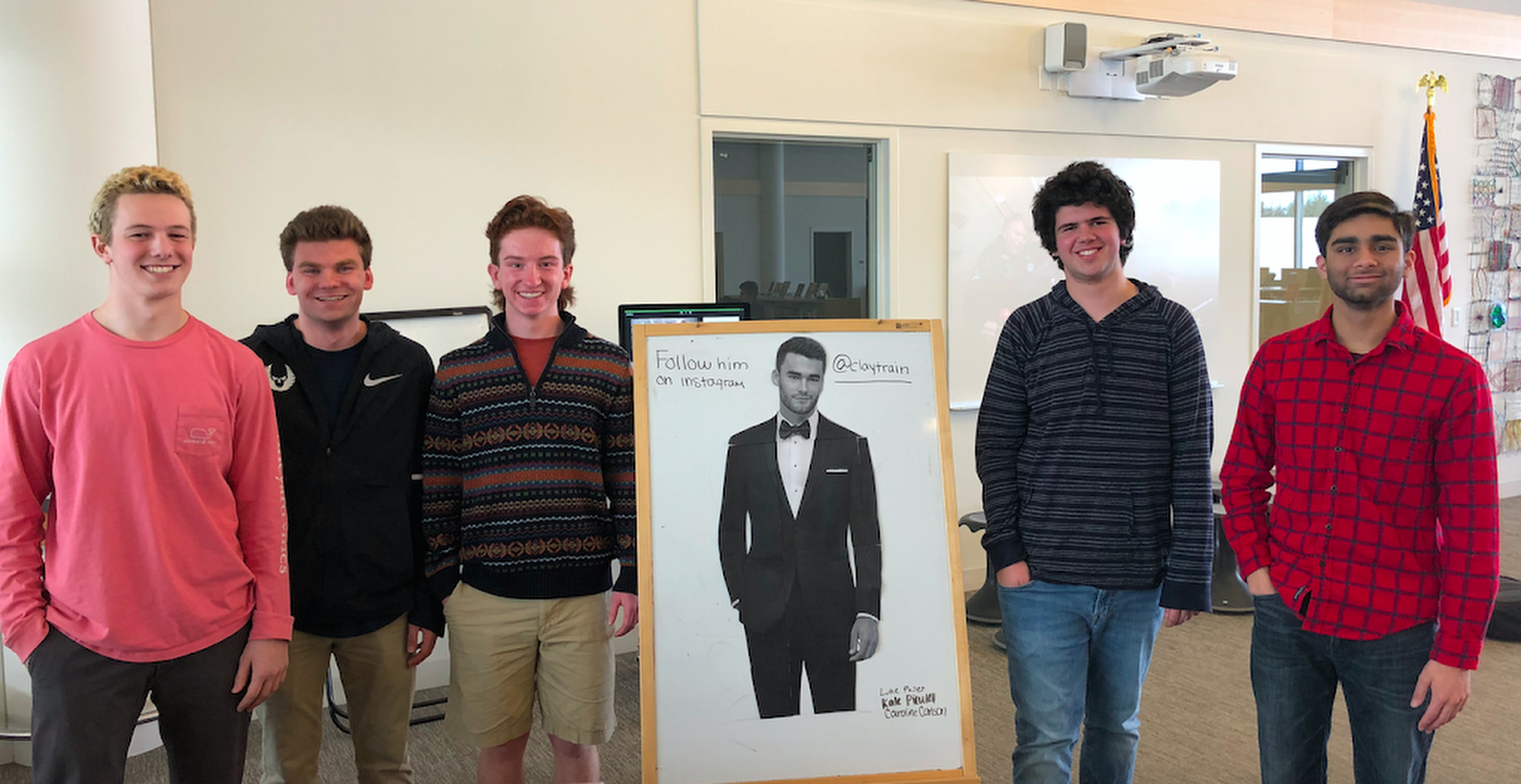 The organizers gathered in the Concord-Carlisle High School library around a poster of tux model Clayton Straker. From left, Luke Pailet, Jake Hamilton, Will Meehan, Spencer Torres, and Aryaman Joshi.