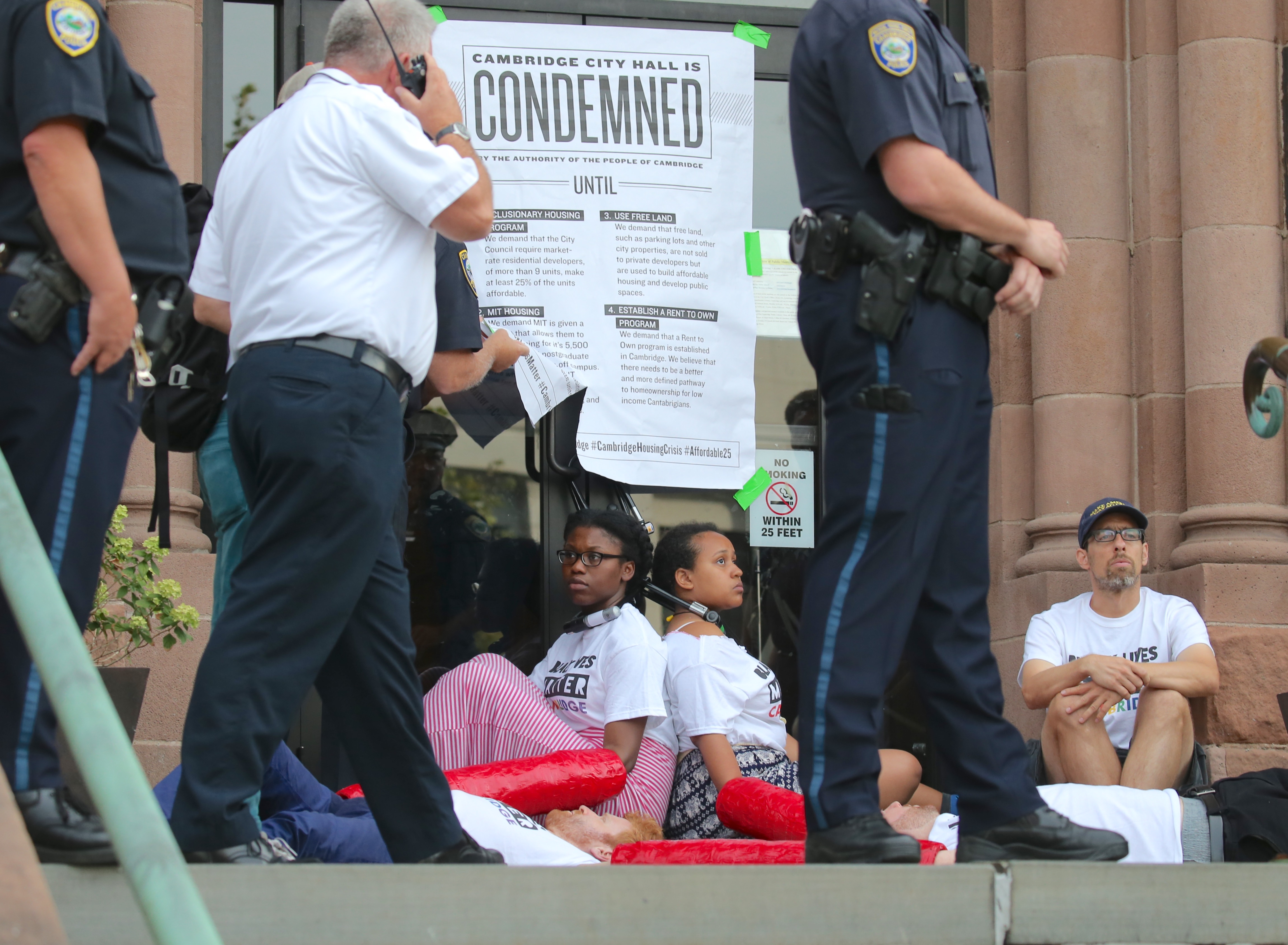 Protesters used bicycle locks and chains to block the front entrance of Cambridge City Hall Wednesday morning.