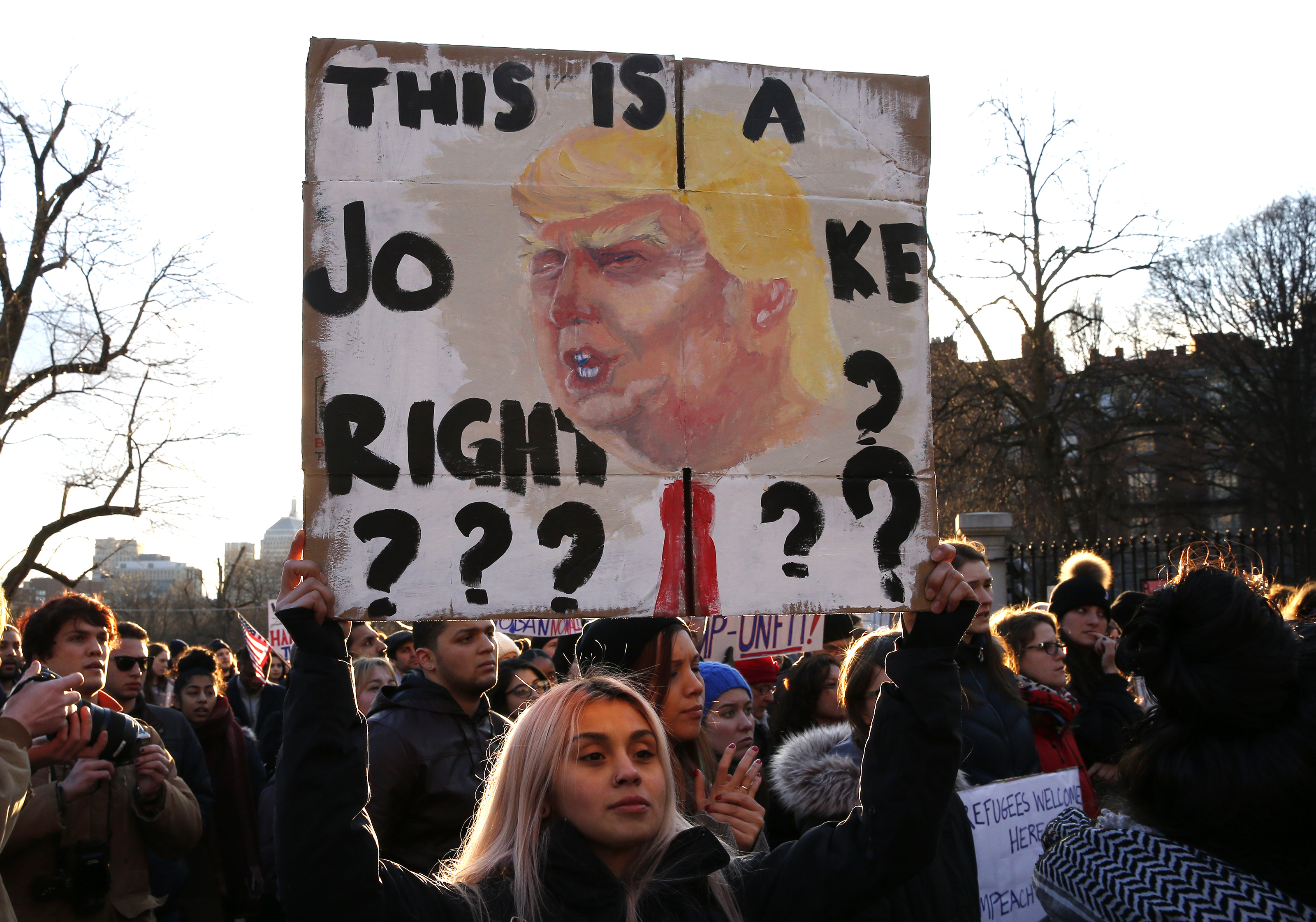 One sign-holding protester posed a rhetorical question outside the State House.