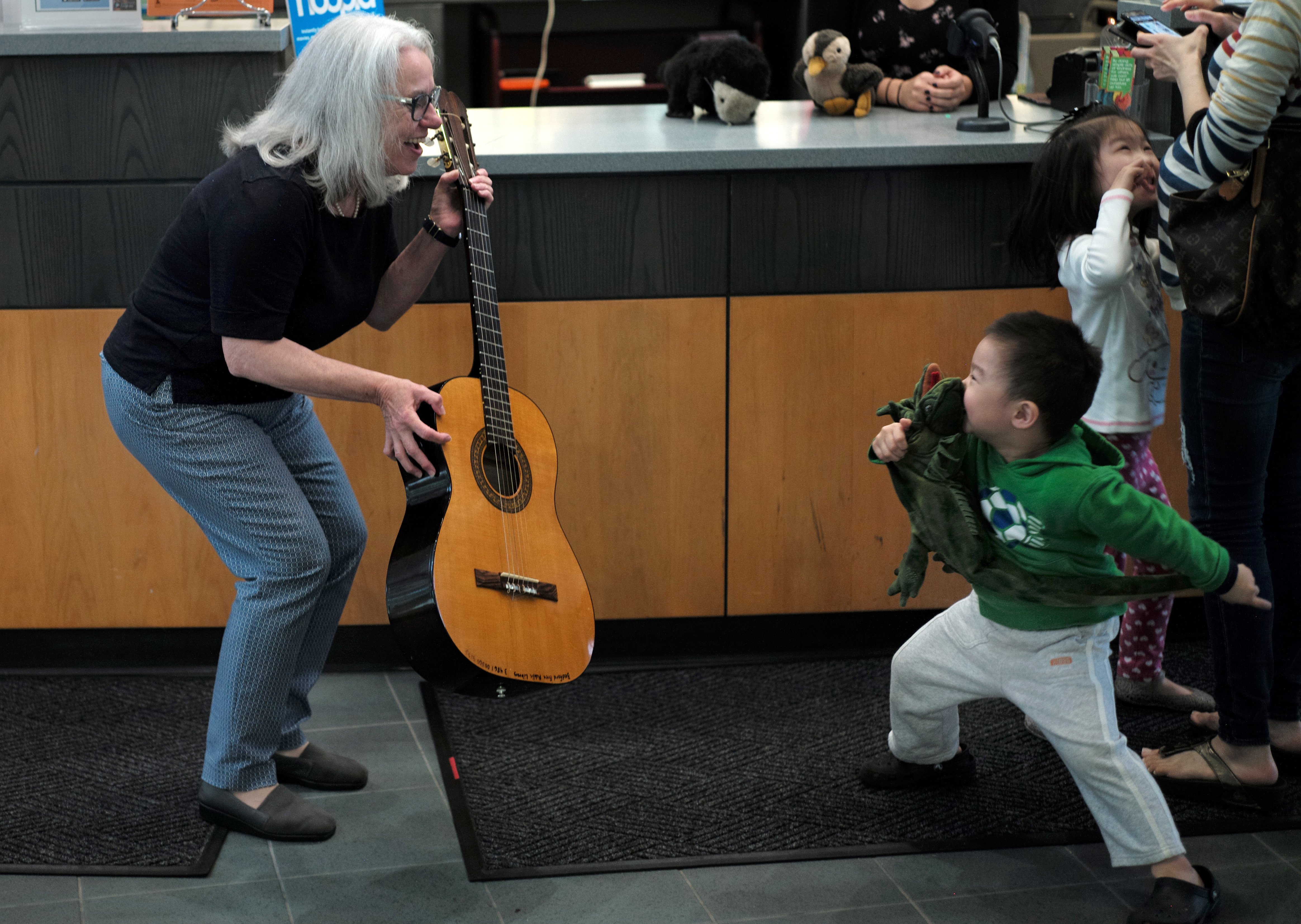 Noreen O'Gara, assistant library director at the Bedford Free Public Library, showed a guitar to a little boy who was about to check out with some items from a display.